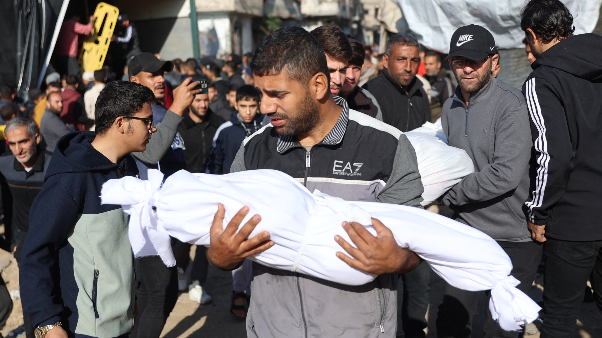 A Palestinian man carries the body of a child killed in an Israeli airstrike on Jabalia in the northern Gaza Strip on 20 November 2024 (Omar al-Qattaa/AFP)