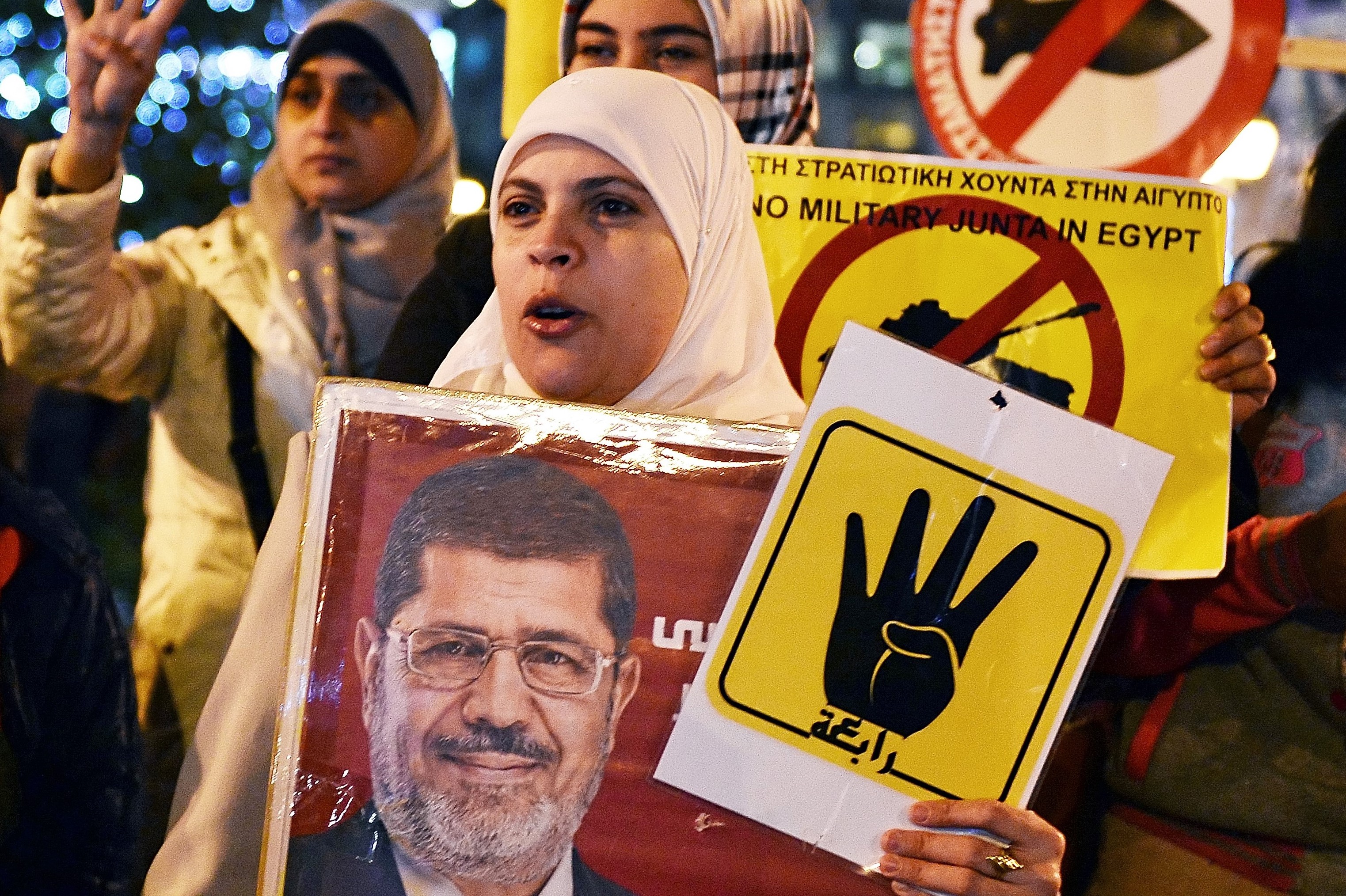 Une femme brandit une bannière de l’ancien président égyptien Mohamed Morsi lors d’une manifestation d’opposition à Sissi à Athènes en décembre 2015 (AFP)