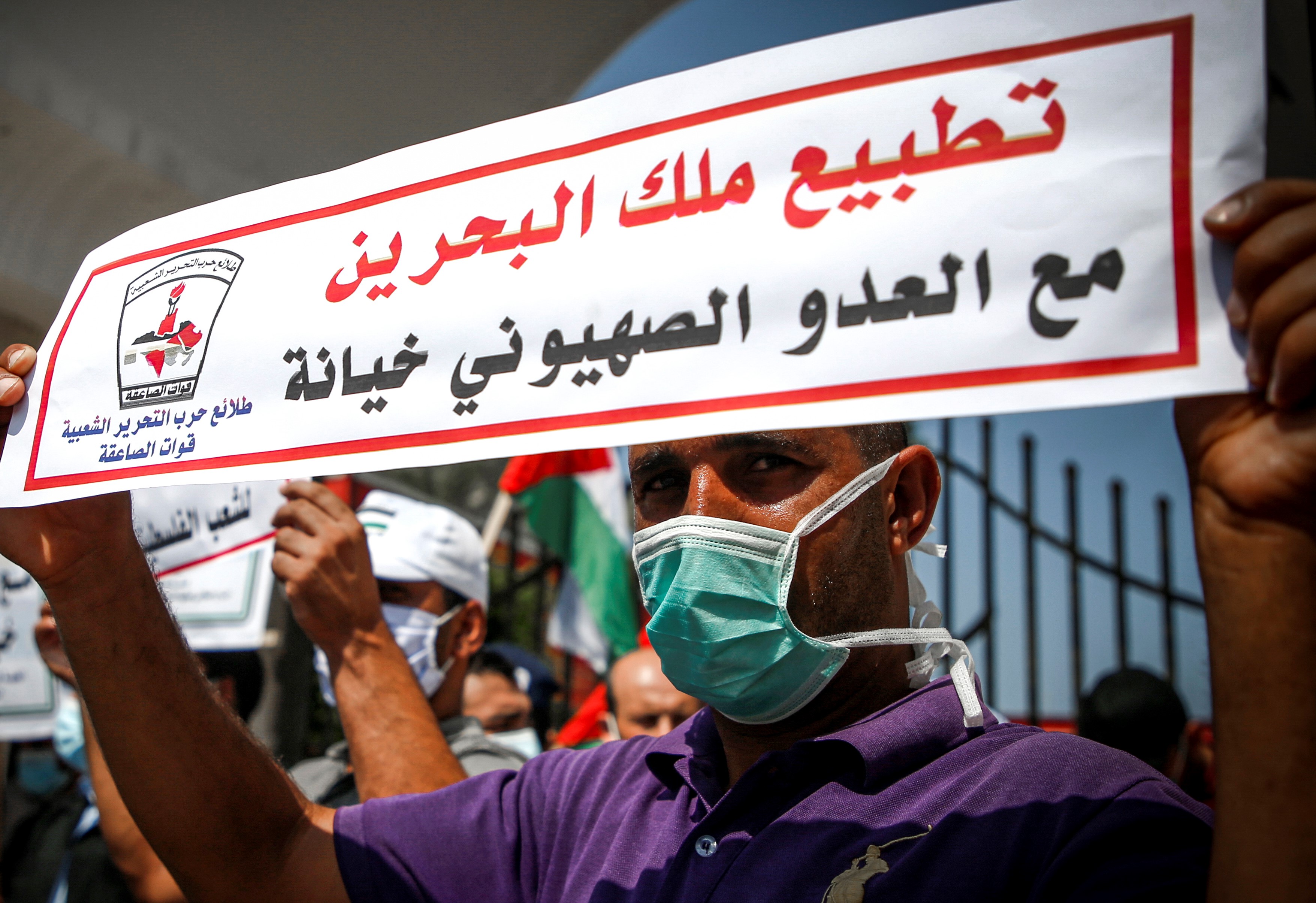 A demonstrator, mask-clad due to the COVID-19 coronavirus pandemic, stands holding a sign reading in Arabic "the King of Bahrain's normalisation with Israel is betrayal" during a protest against the United Arab Emirates' and Bahrain's decisions to normalise relations with Israel, in Gaza City on September 15, 2020.