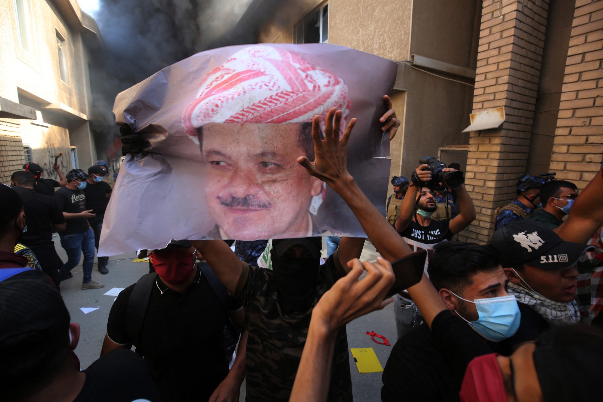 Iraqi supporters of pro-Iranian groups tear up a portrait of Massoud Barzani in Baghdad in October 2020 (AFP)