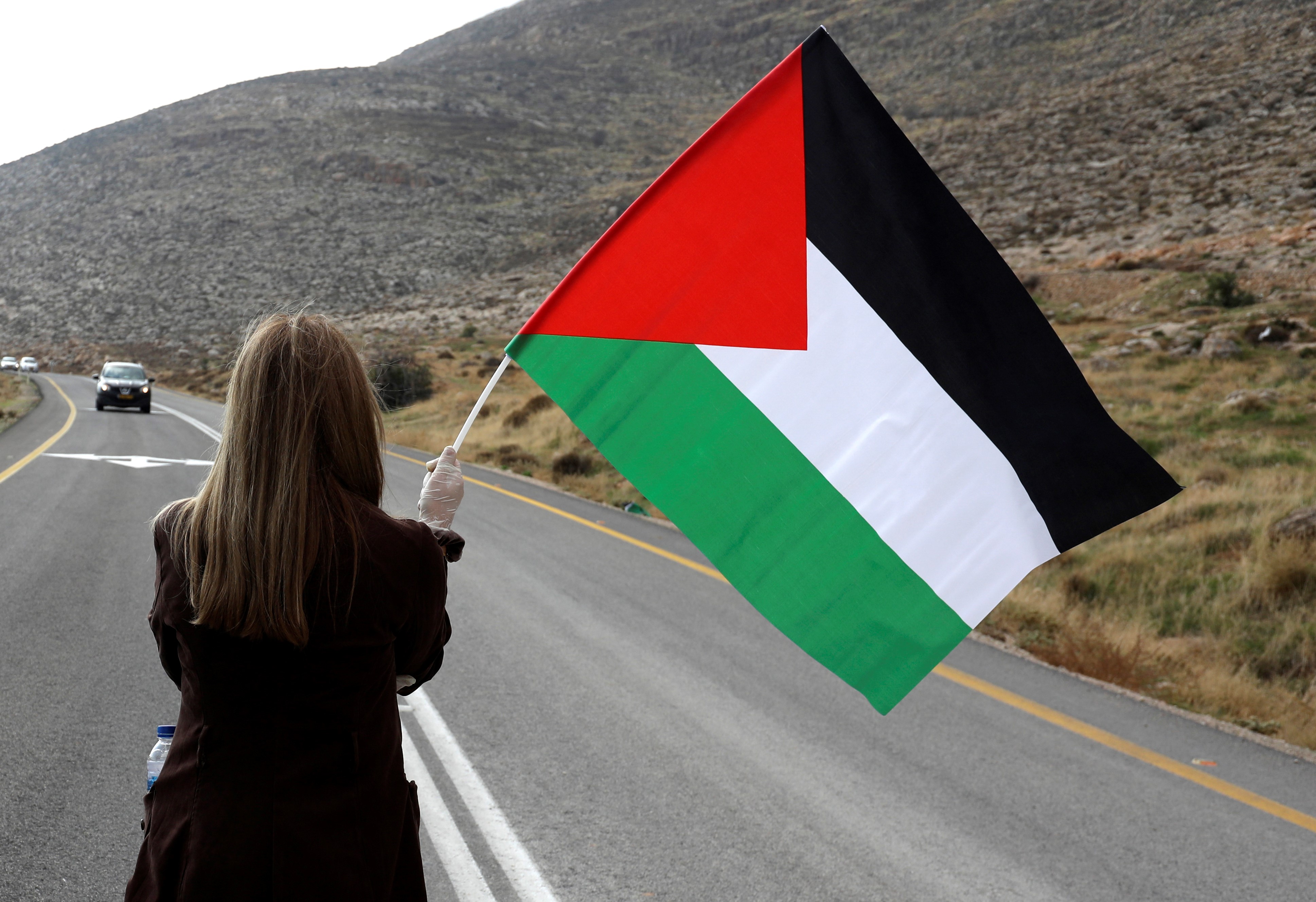 A Palestinian woman stands in middle of a road to stop Israeli settlers from passing during a demonstration against Jewish settlements in the village Kafr Malik in the Israeli-occupied West Bank, on November 20, 2020