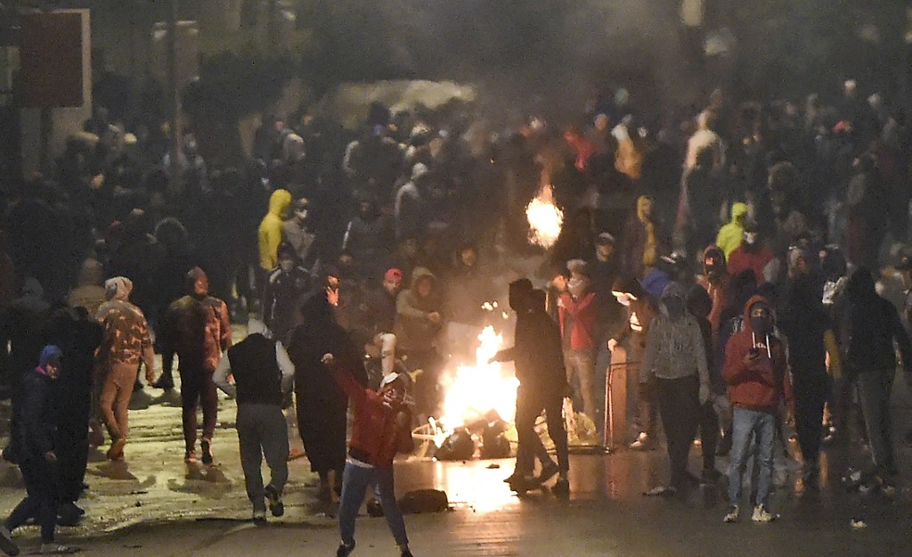 Protesters block a street during clashes with the police in Ettadhamen on 18 January 2021 (AFP)