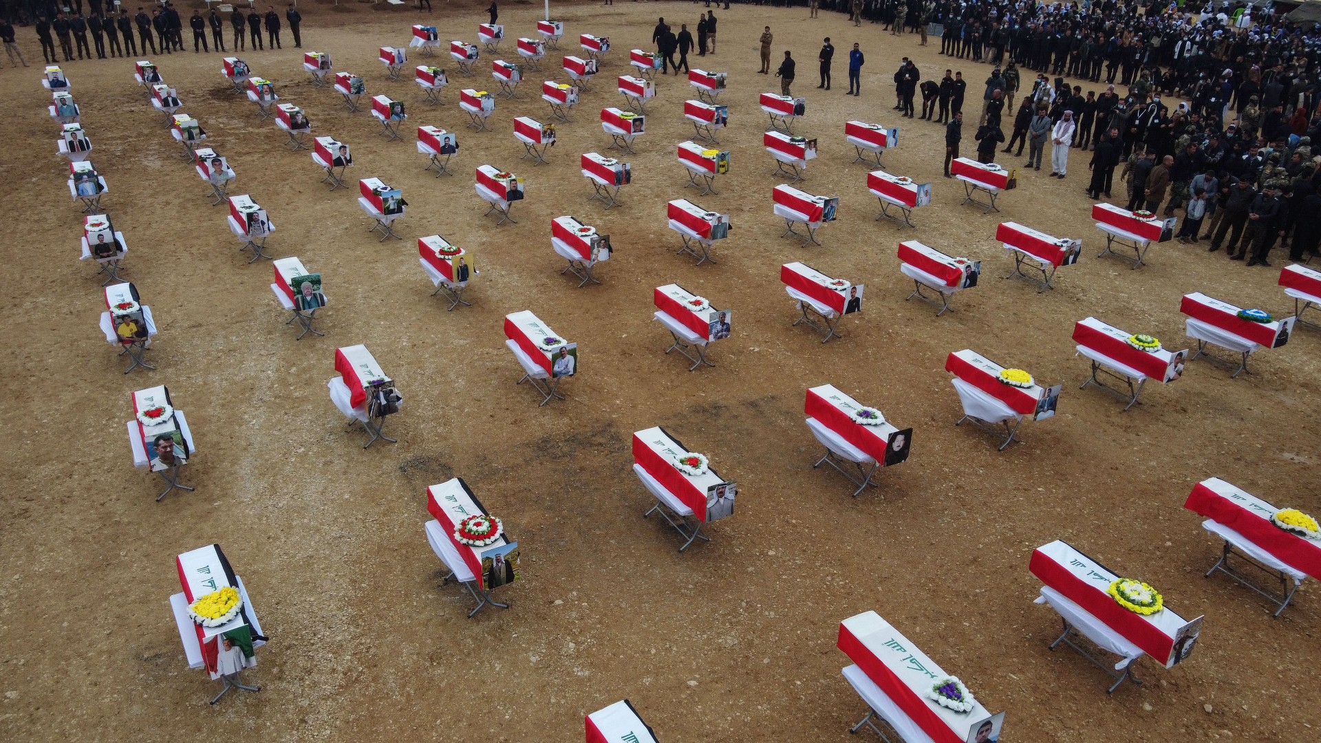 An aerial picture shows mourners gathering around coffins wrapped with the Iraqi flag during a mass funeral for Yazidi victims of the Islamic State group near Sinjar (AFP)