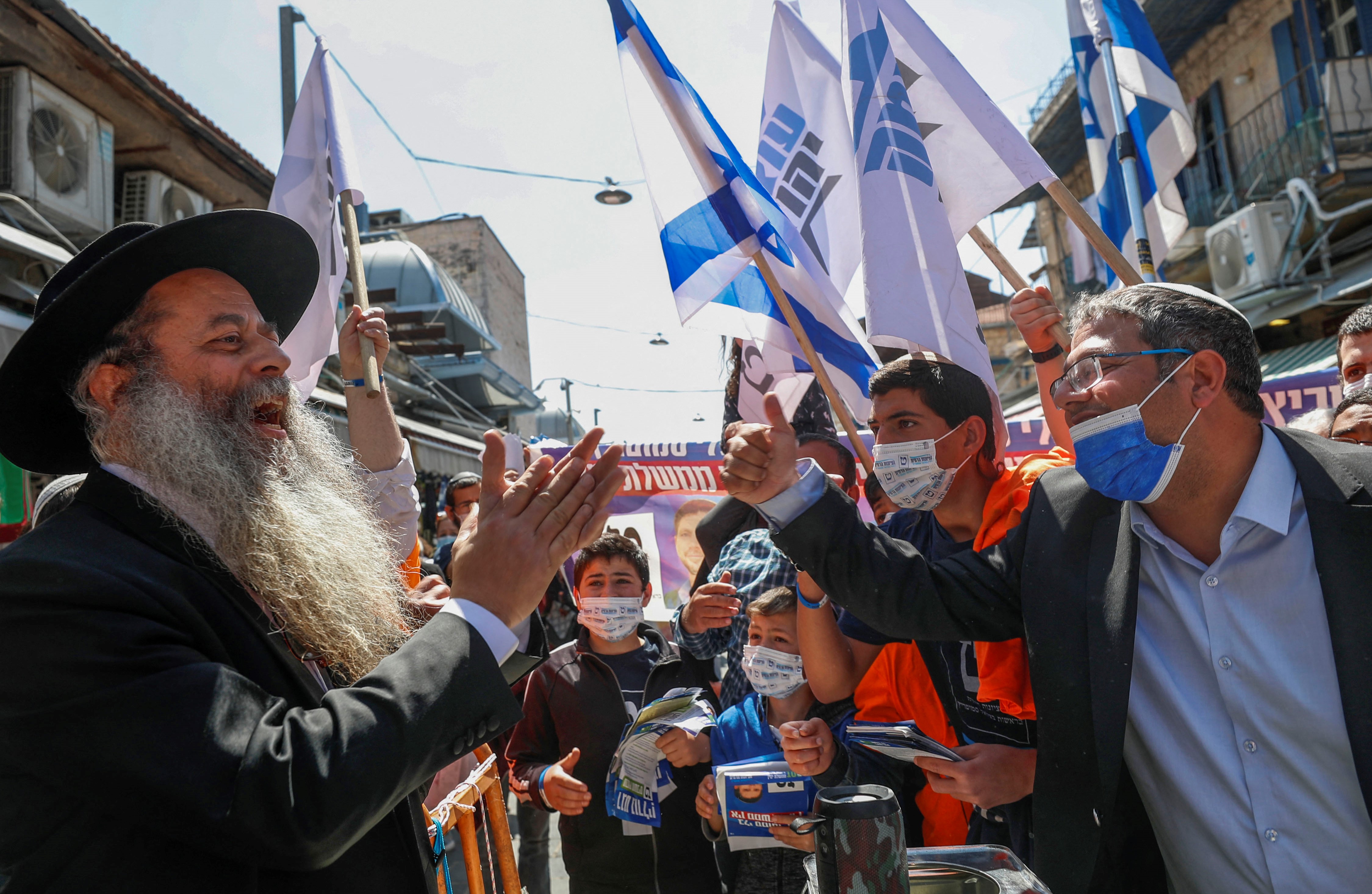 Head of Israel's Jewish Power (Otzma Yehudit) party Itamar Ben Gvir (R) talks to supporters through Mahane Yehuda market in Jerusalem, on 19 March (AFP)