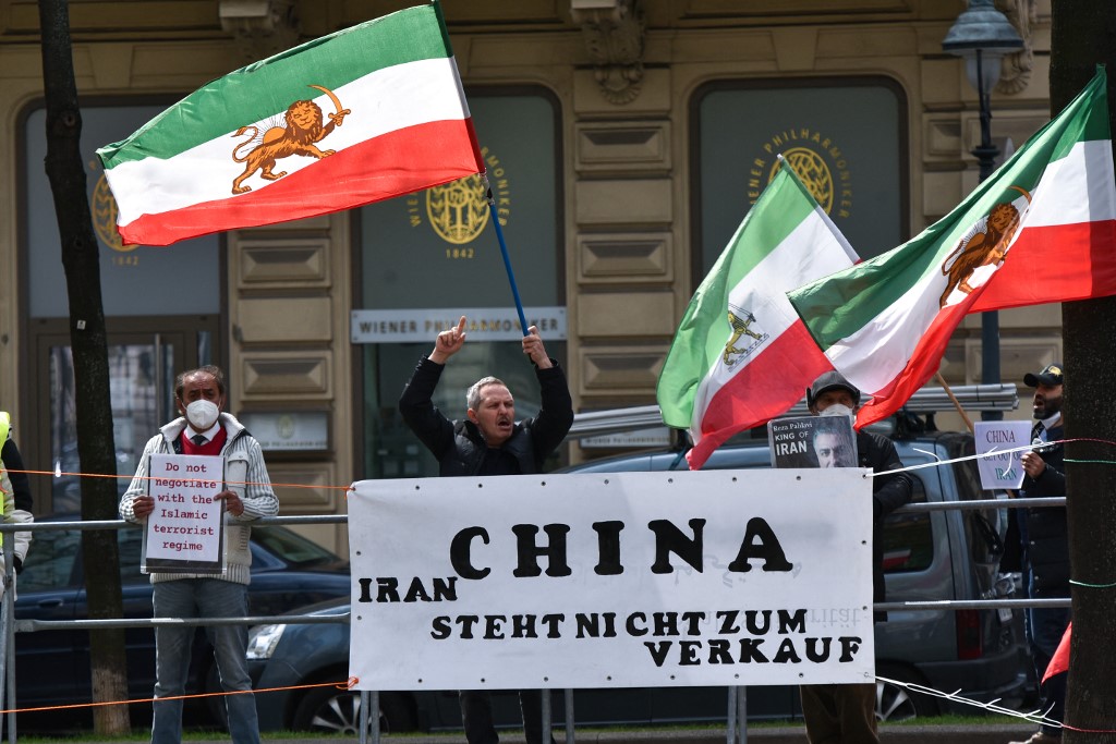 Protesters stand behind a banner reading 'China - Iran is not for sale' outside the closed-door nuclear talks with Iran in Vienna,
