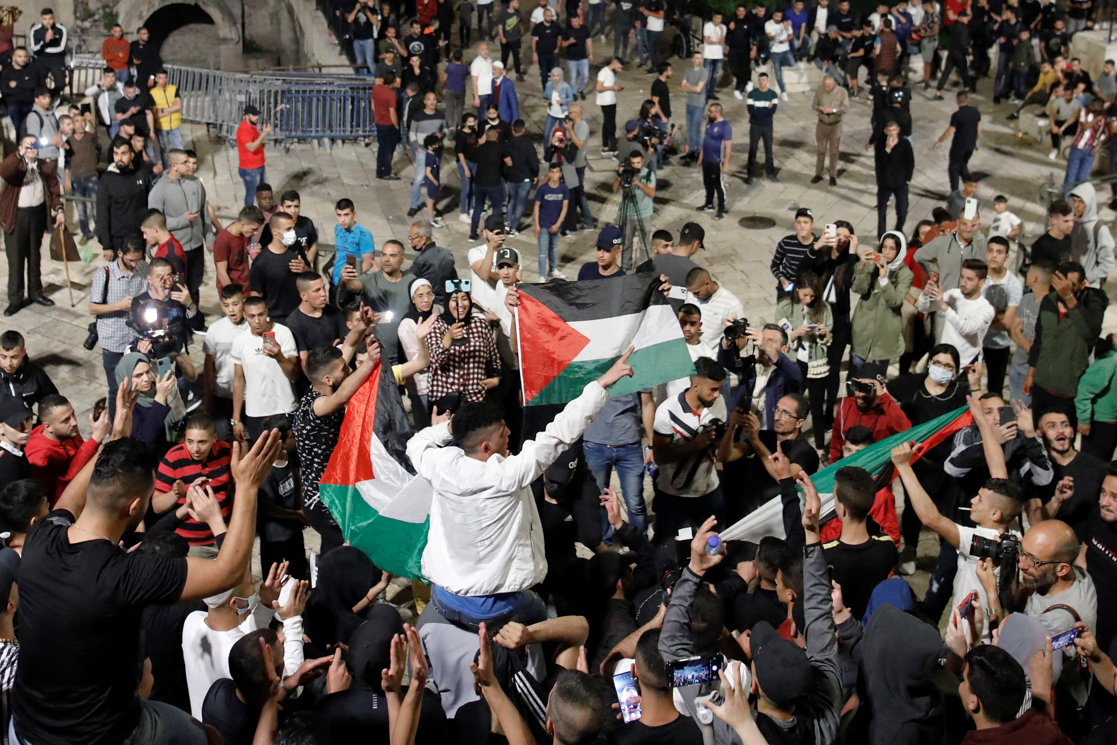 Palestinian protesters raise national flags as they gather near the Damascus Gate in Jerusalem's Old City, on April 25, 2021.