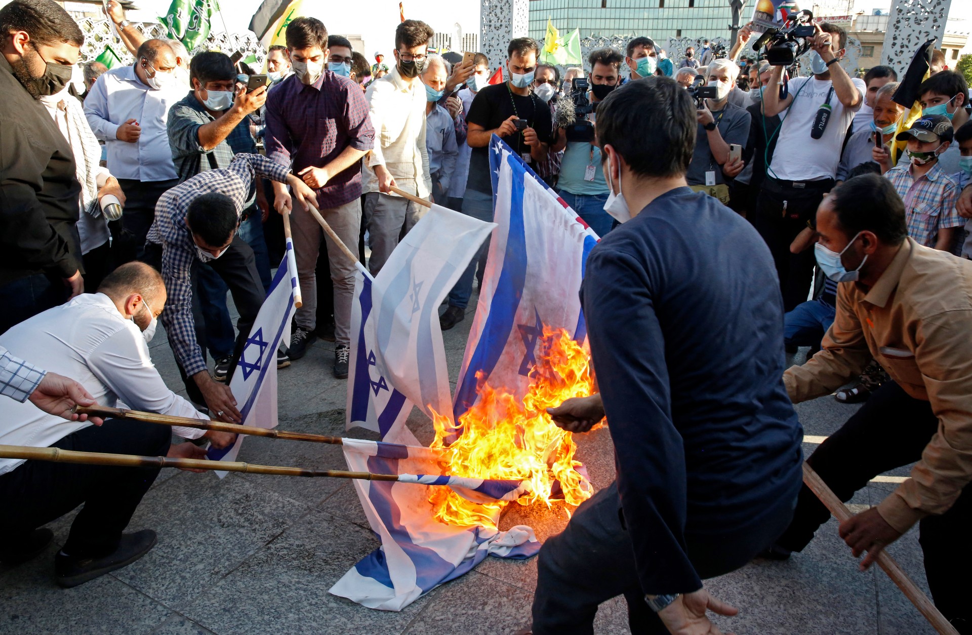 Iranians burn Israeli flags during a march to condemn the ongoing Israeli air strikes on the Gaza Strip, in the capital Tehran's Palestine square, on 19 May (AFP)