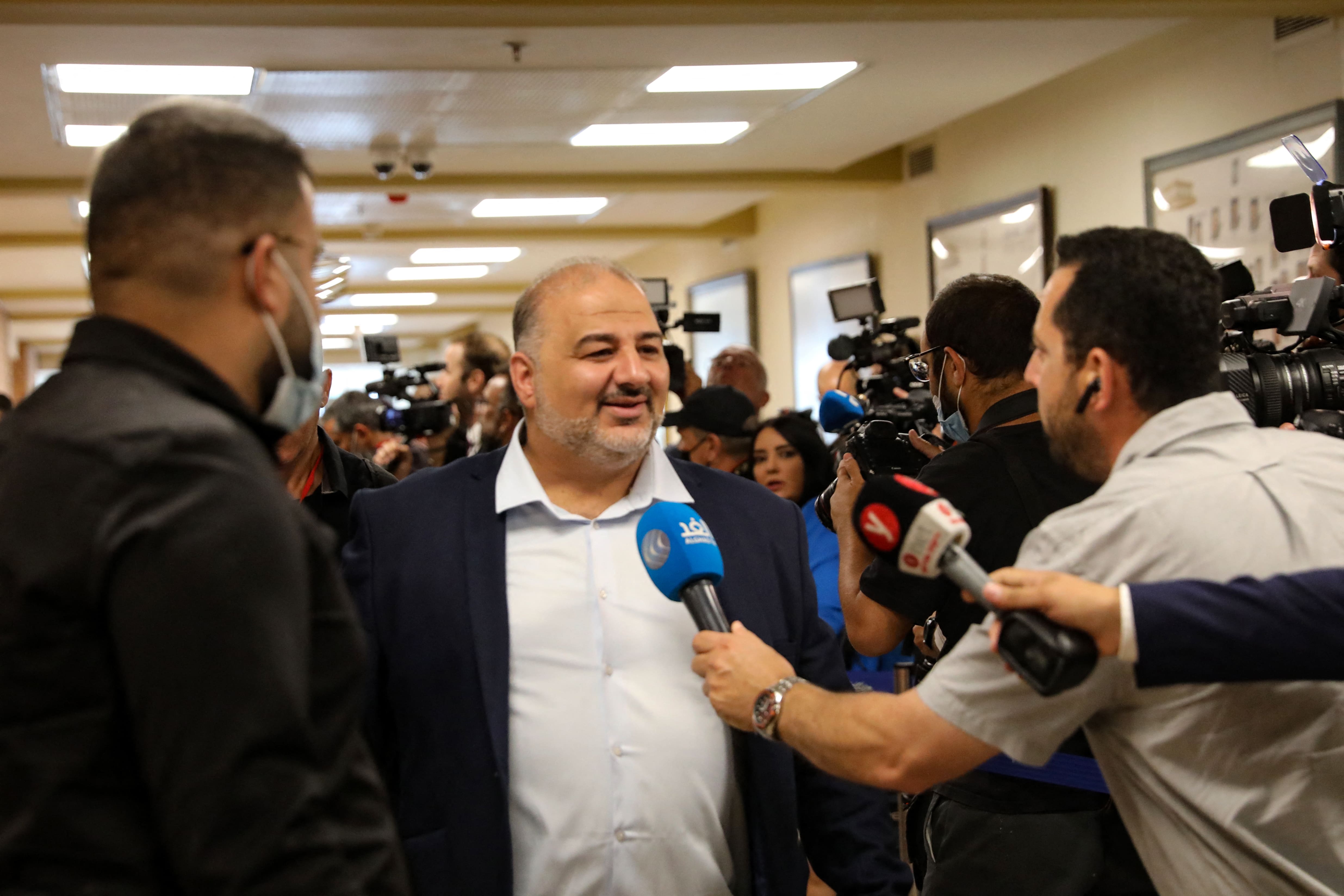 Mansour Abbas of the Islamic Raam party surrounded by members of the media as he arrives to attend a parliamentary meeting at the Knesset, ahead of a vote on a new government, on 13 June, 2021 (AFP)
