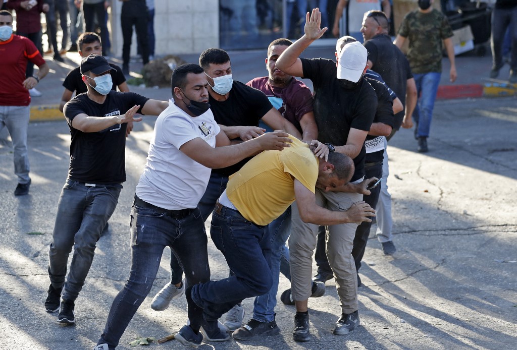 Palestinian plainclothed security officers detain a man during a demonstration in the city of Ramallah in the occupied West Bank, on 26 June 2021.