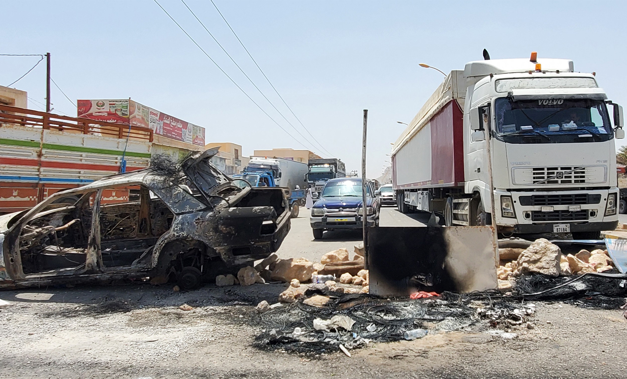 Cars and cargo trucks are stuck at a roadblock set by Yemeni protesters on the international road leading to the border crossing with Oman, in Hadhramaut's Tarim (AFP)