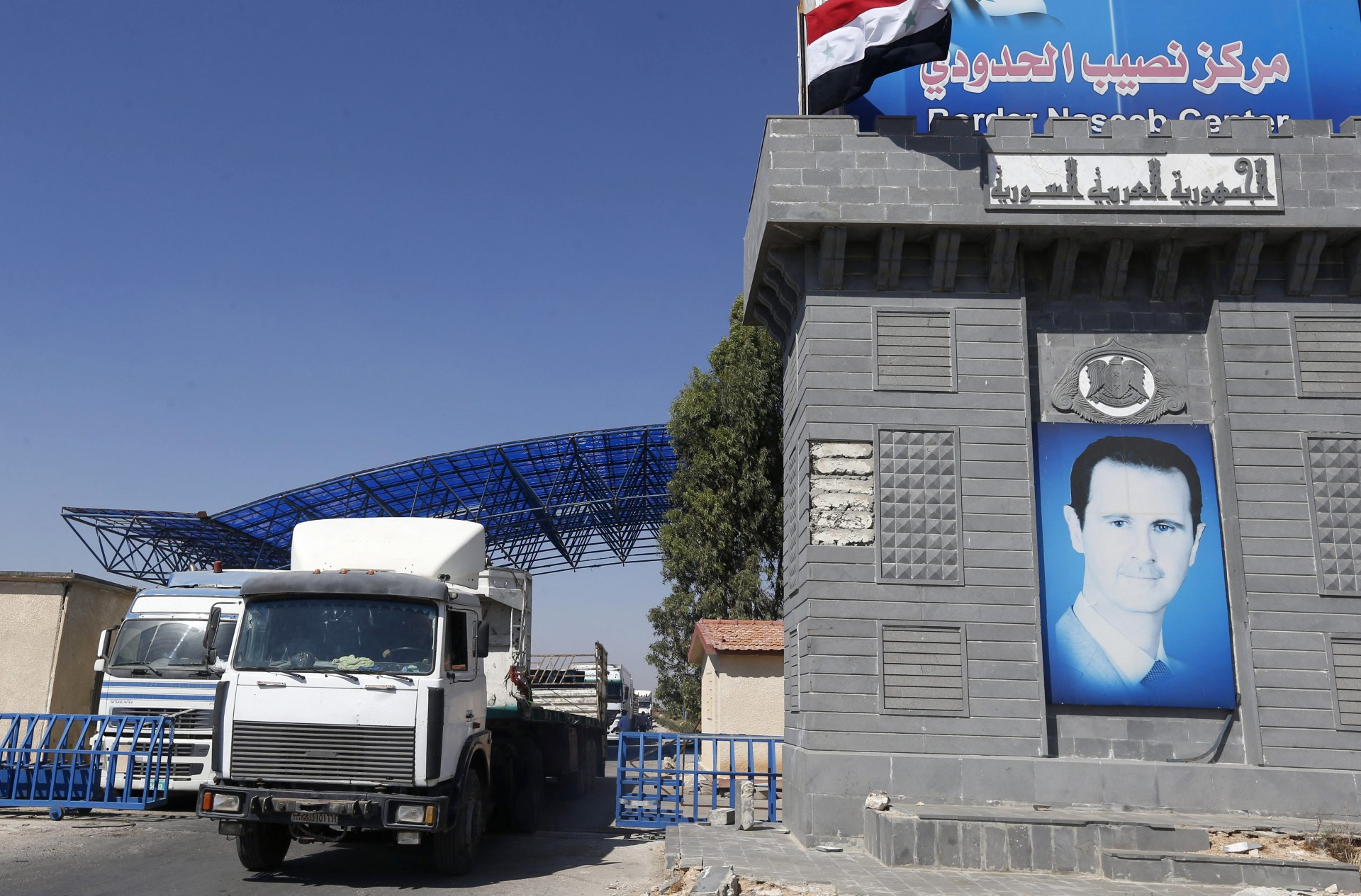 Trucks enter Syria through the Nassib border crossing with Jordan (AFP)