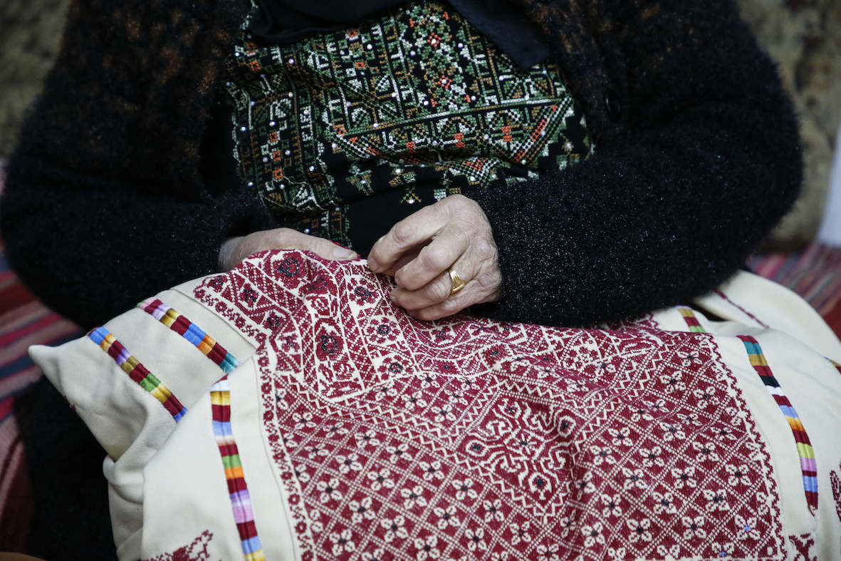 a Palestinian woman embroiders a traditional Palestinian dress (AFP/ Hazem Bader)