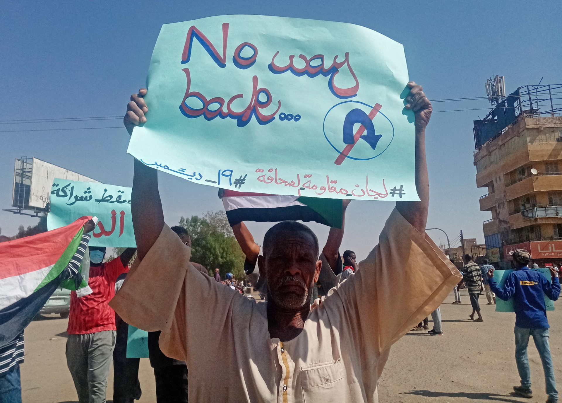 A Sudanese man carries a placard during a rally to mark three years since the start of mass demonstrations that led to the ouster of Bashir, on 19 December 2021 (AFP)