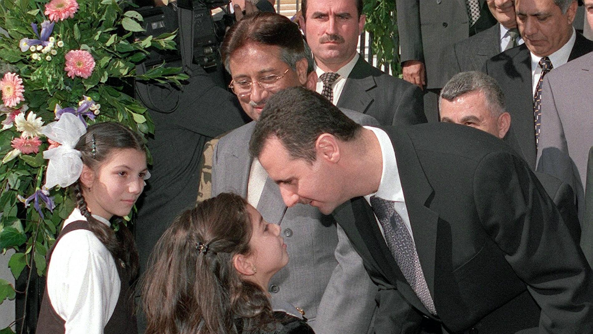 Syrian President Bashar al-Assad kisses a schoolgirl at the Pakistan International School in Damascus as Pakistani military ruler Pervez Musharraf looks on in 2001 (AFP)