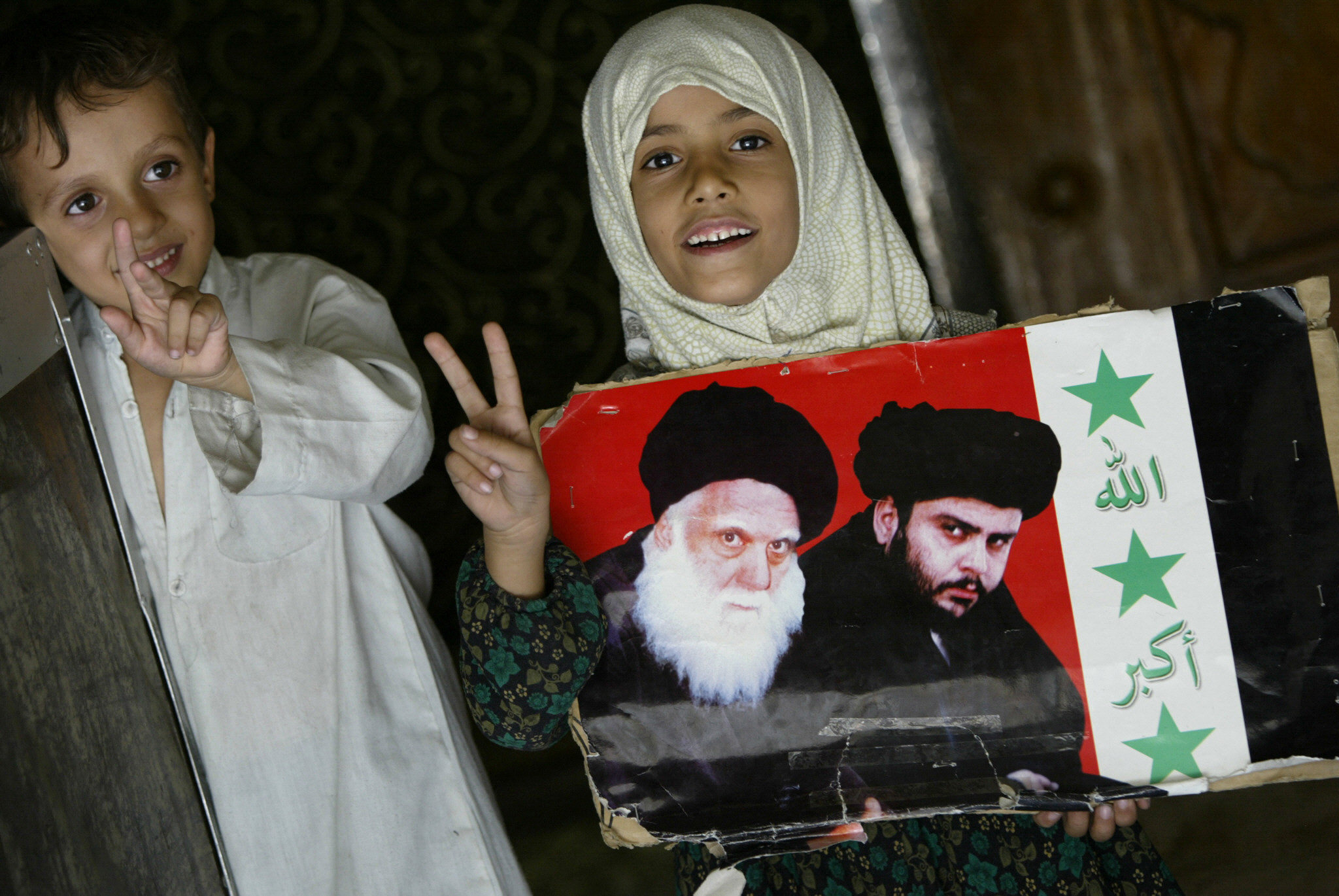 A young girl holding a picture of Muqtada al-Sadr (R) and his assassinated father Mohammed Sadeq al-Sadr (AFP)