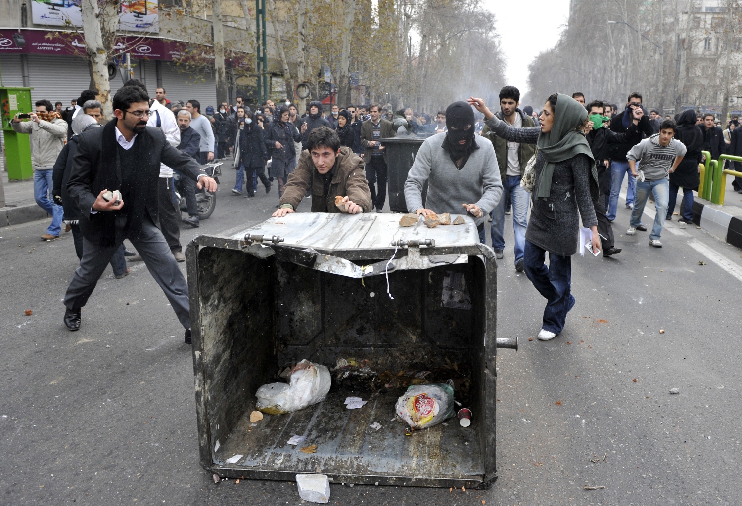 Iranian opposition supporters push a garbage container during clashes with security forces in Tehran on December 27, 2009 (AFP)