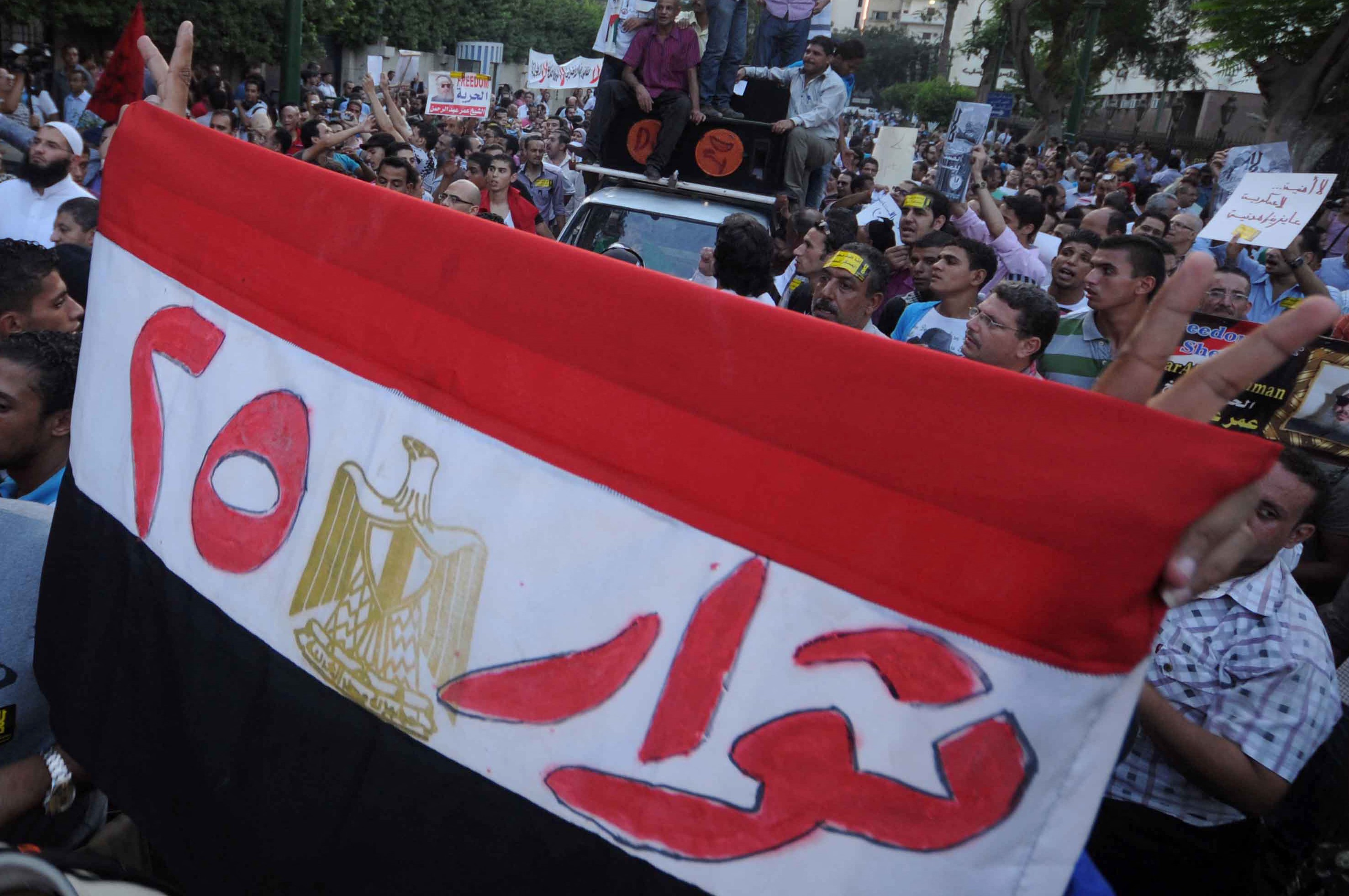 An Egyptian protester holds his national flag bearing the slogan "Revolutionaries of the 25th" - refering to the revolution