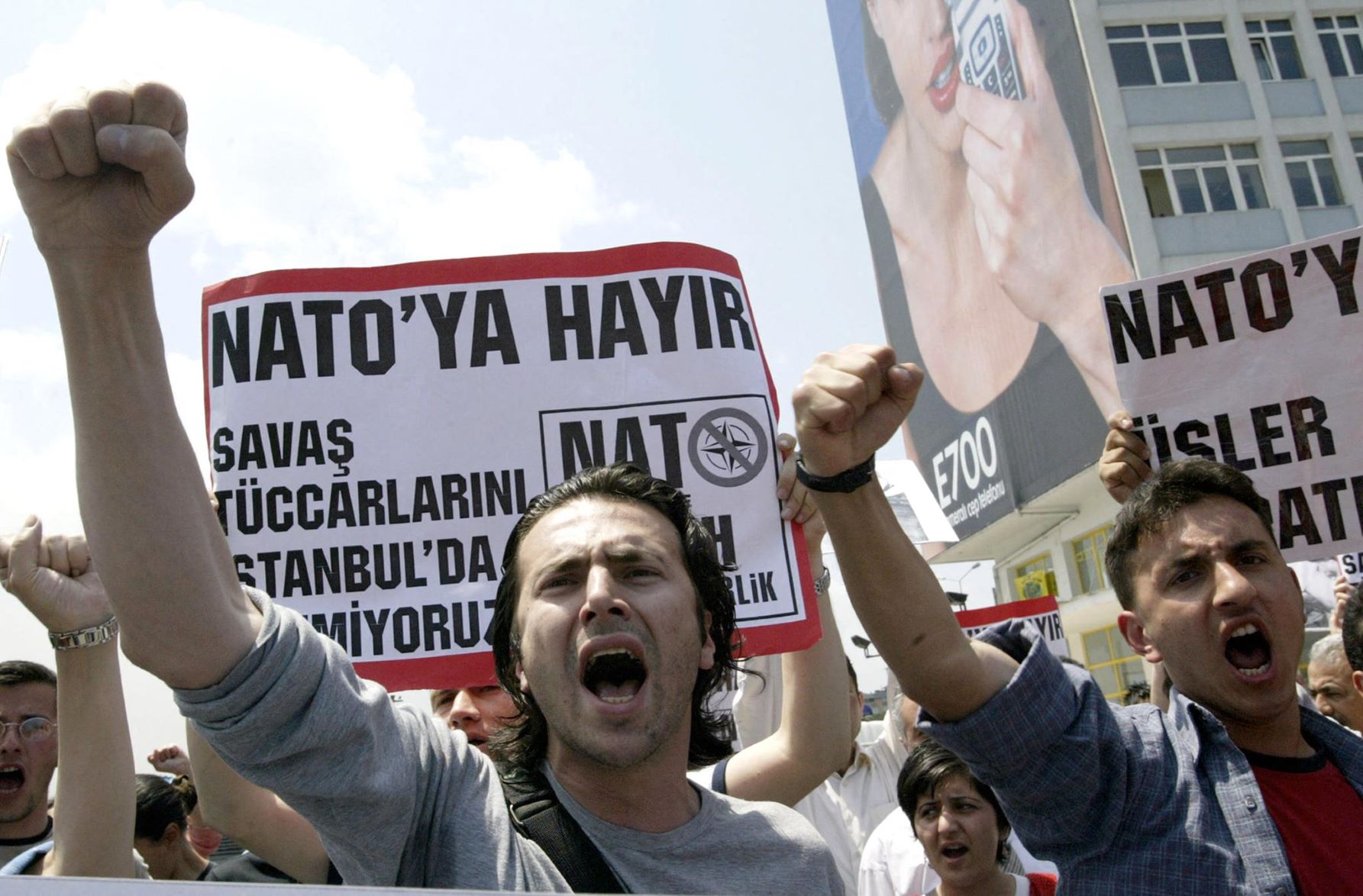 Two Turkish protestors chant slogans "We don`t want NATO" as the others hold banner that reads "No to Nato" during the demonstration against the upcoming NATO meeting in downtown Istanbul, 2004 (AFP)