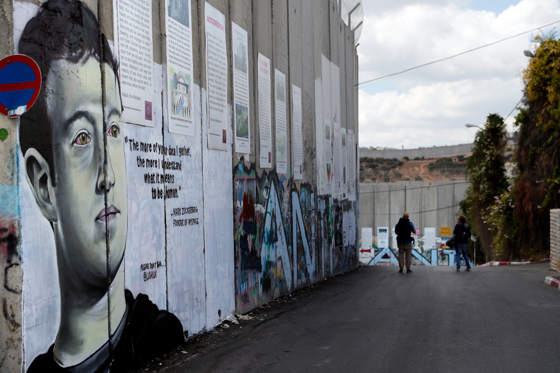 Two men walk past a new piece of graffiti depicting founder of Facebook Mark Zuckerberg on the Israeli separation barrier separating Bethlehem and Jerusalem in 2017 (AFP)