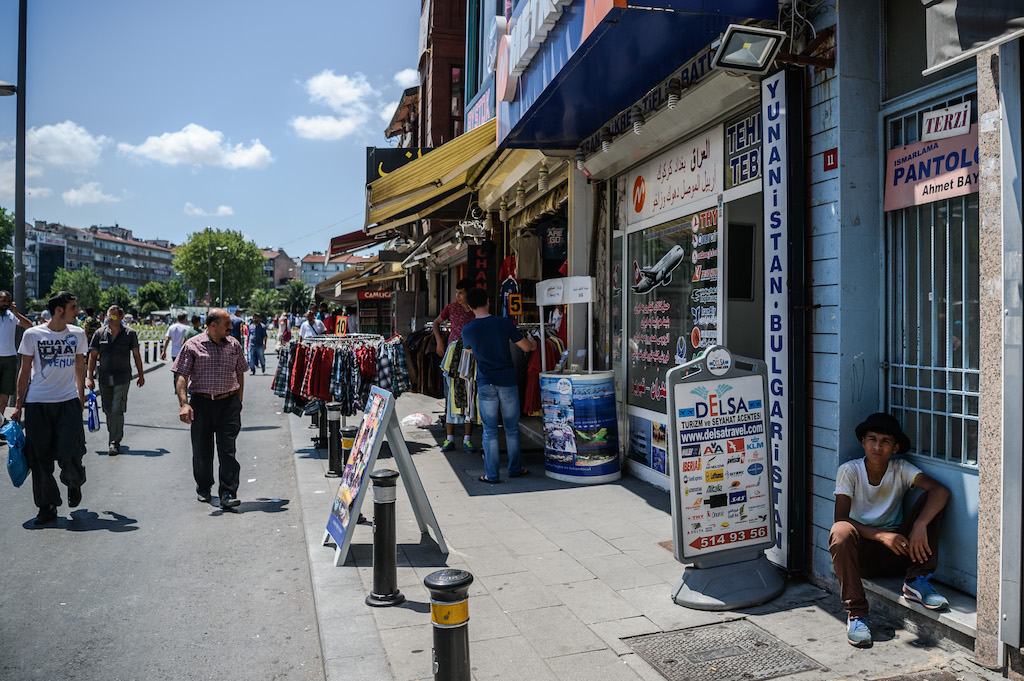 Syrian and Turkish people walk in a street next to shops with Arabic letters on July 4 ,2016 in Fatih neighbourhood in Istanbul (AFP)
