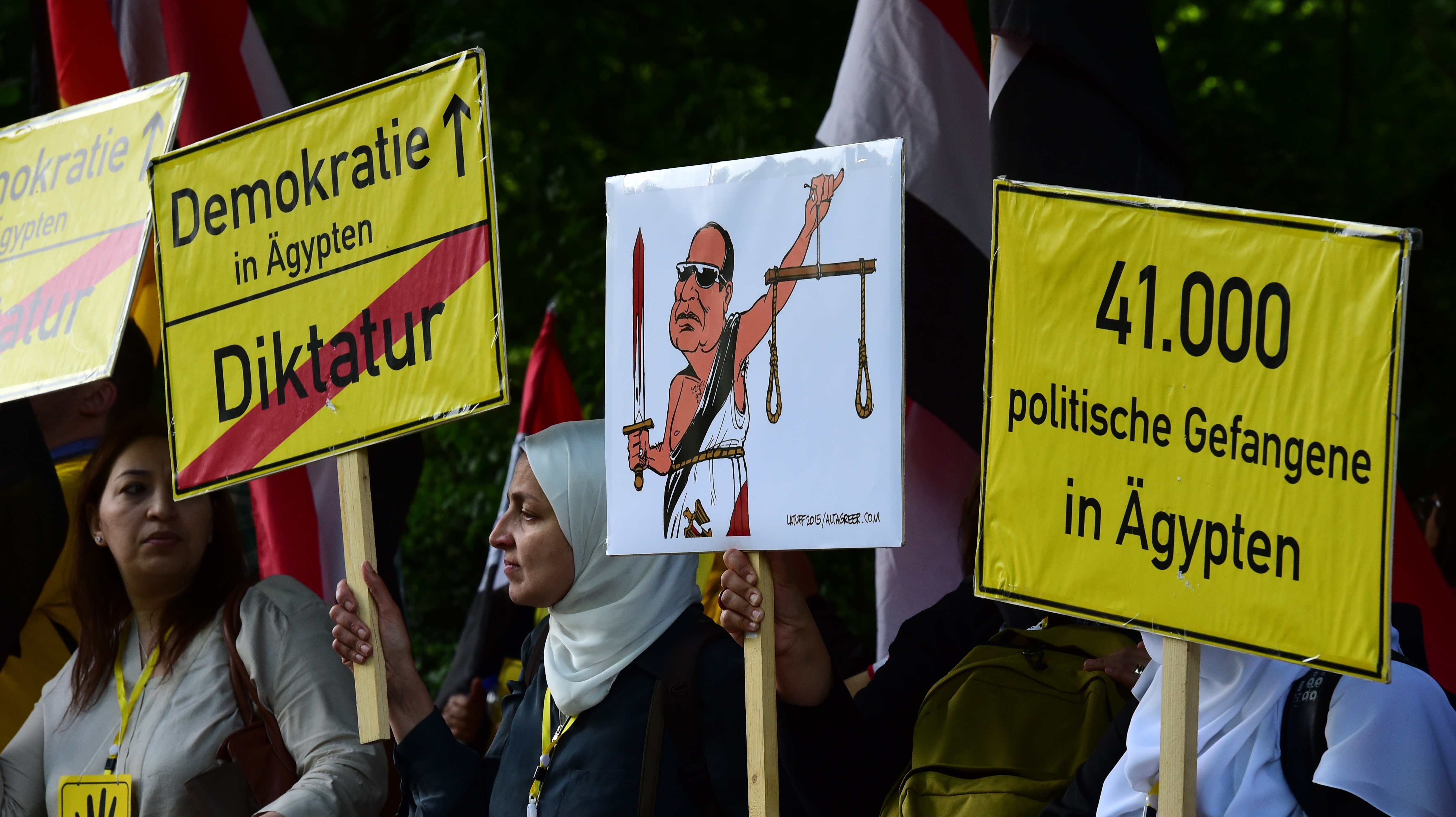 Des manifestants tiennent des banderoles portant l’inscription « Démocratie en Égypte – Dictature » avant l’arrivée de Sissi pour une réunion avec le président allemand à Berlin en 2015 (AFP)