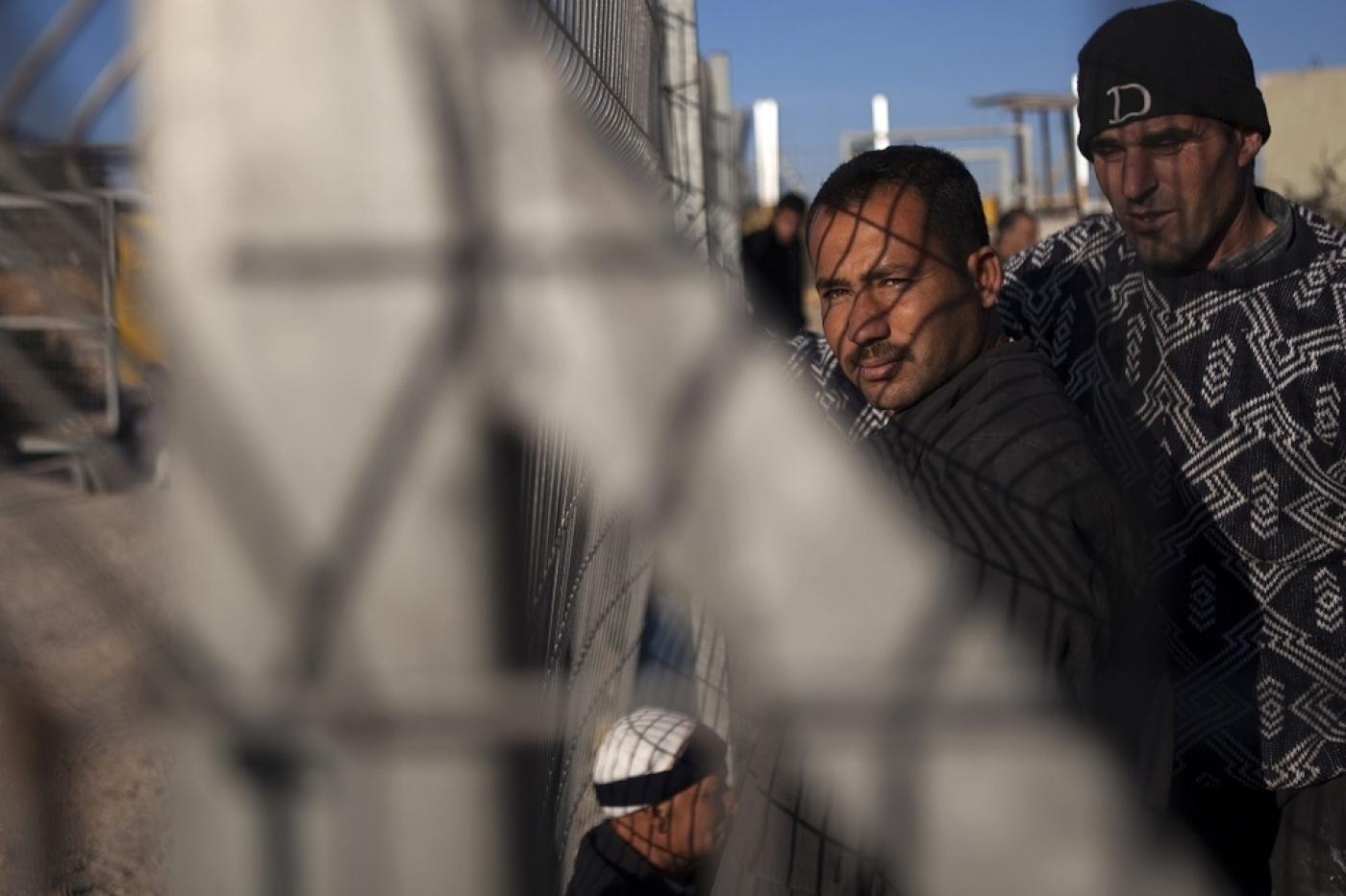 Des travailleurs palestiniens attendent l’ouverture d’un portail entre la colonie illégale de Modiin Illit et le village cisjordanien de Harbeta après leur journée de travail en Israël (AFP)