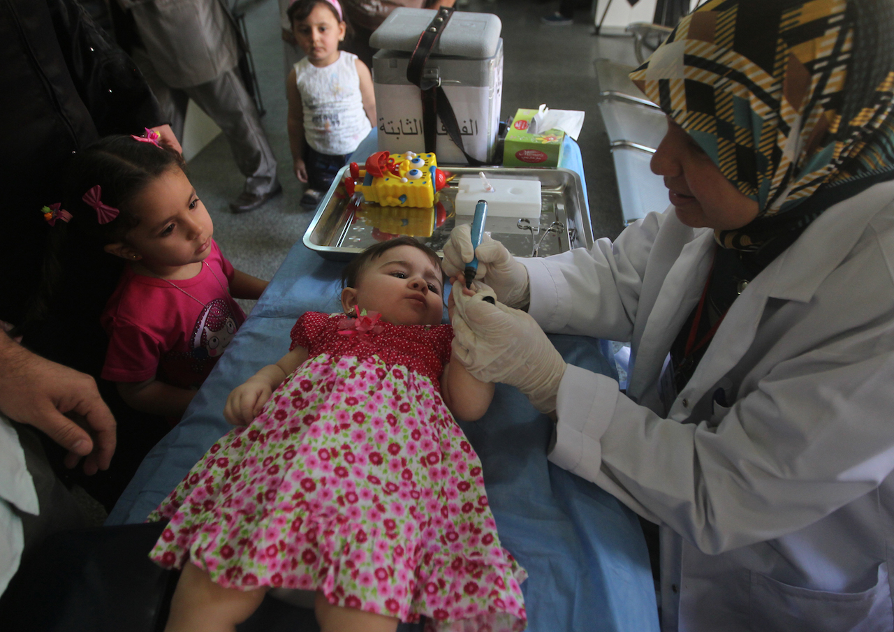 An Iraqi doctor marks a child after giving her a polio vaccine to a child at a health clinic in Baghdad (AFP)