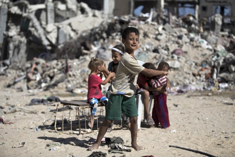 Palestinian children play next to the rubble of buildings destroyed in the 2014 Gaza war (AFP)