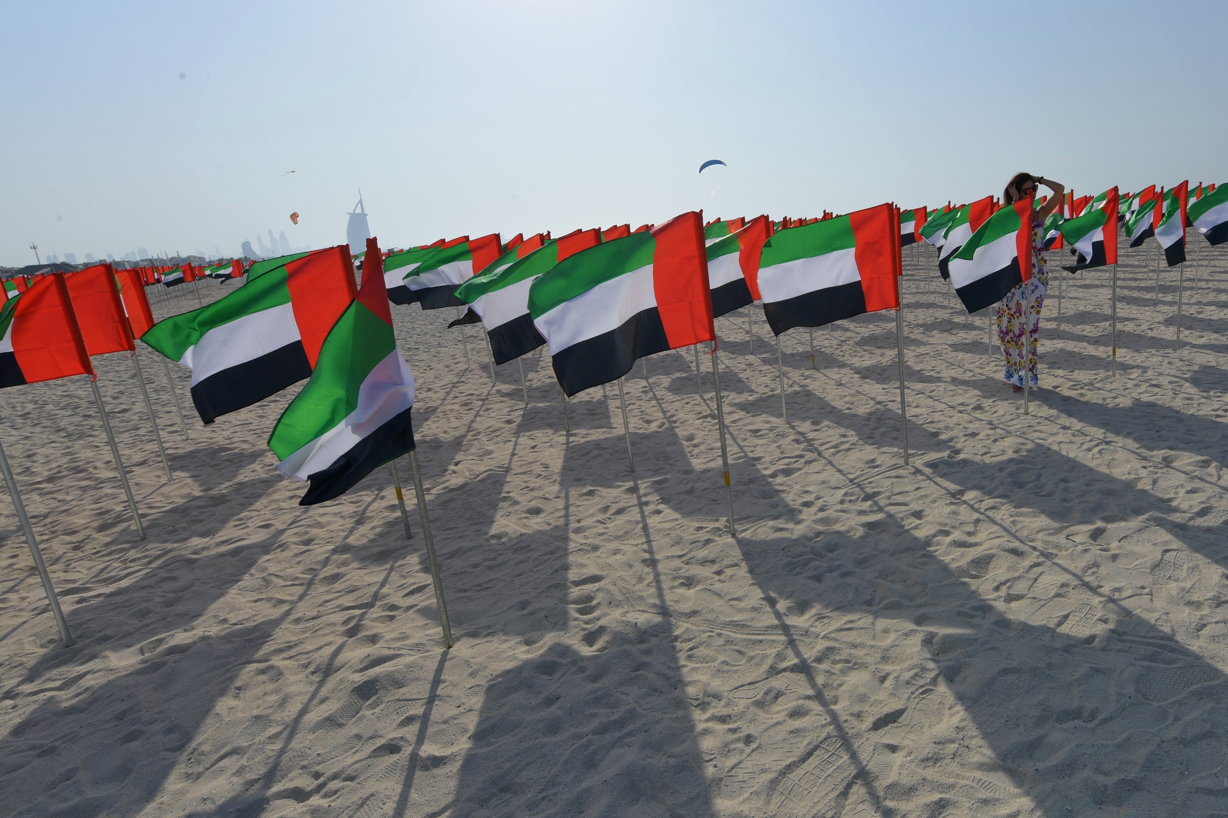 A girl poses next to UAE flags on the eve of the Flag Day at Kite Beach in Dubai on November 2, 2017