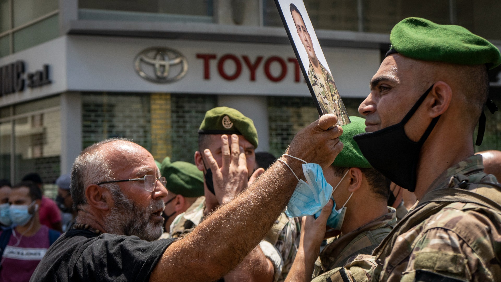 A man holds a photograph of a relative killed in the Beirut port explosion during a protest on 9 July, 2021 (MEE/Matt Kynastan)