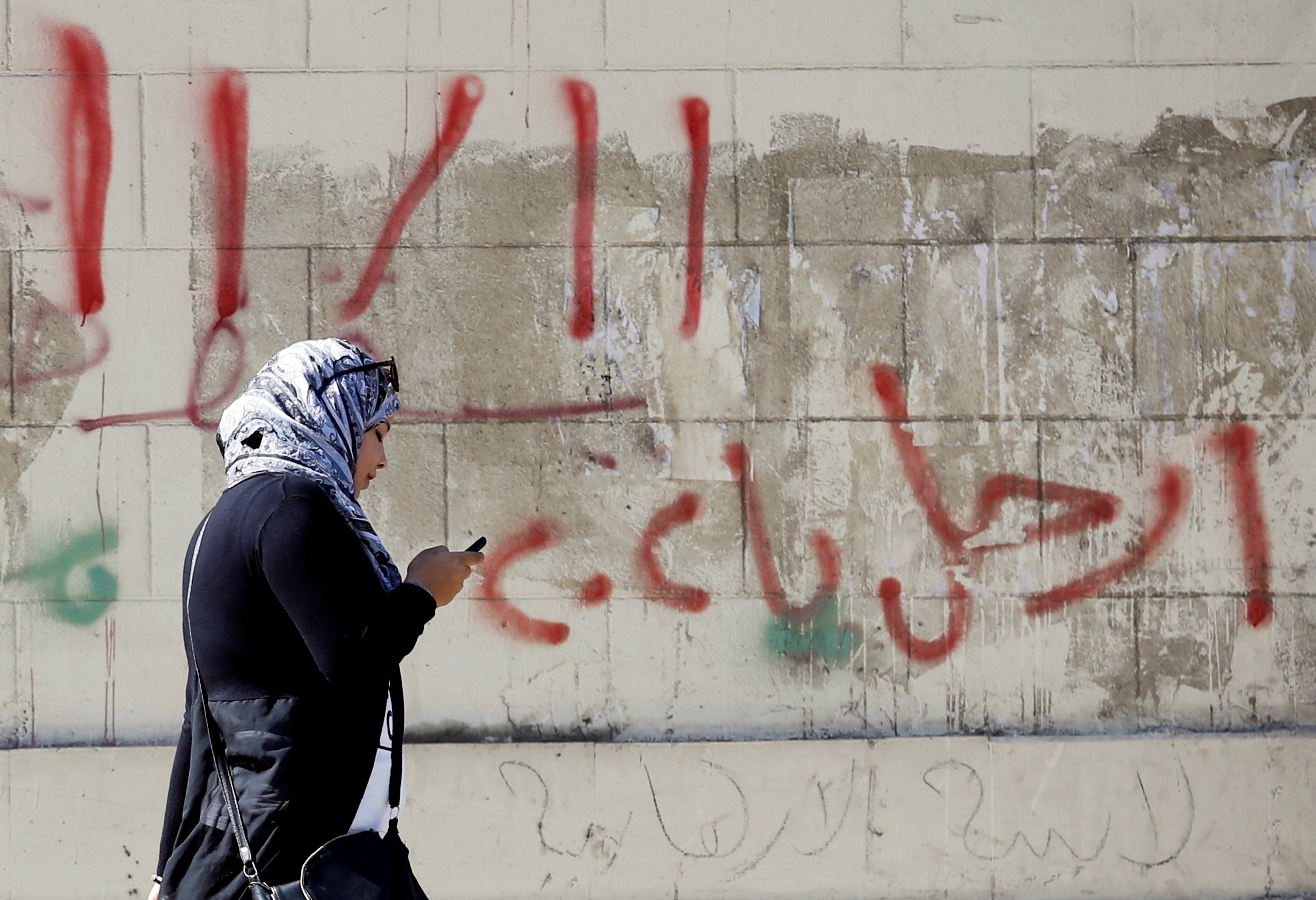 A woman in front of a wall with graffiti calling on Egyptians to participate in demonstrations against economic conditions following the rise of prices around the country 9 November, 2016 (Reuters)