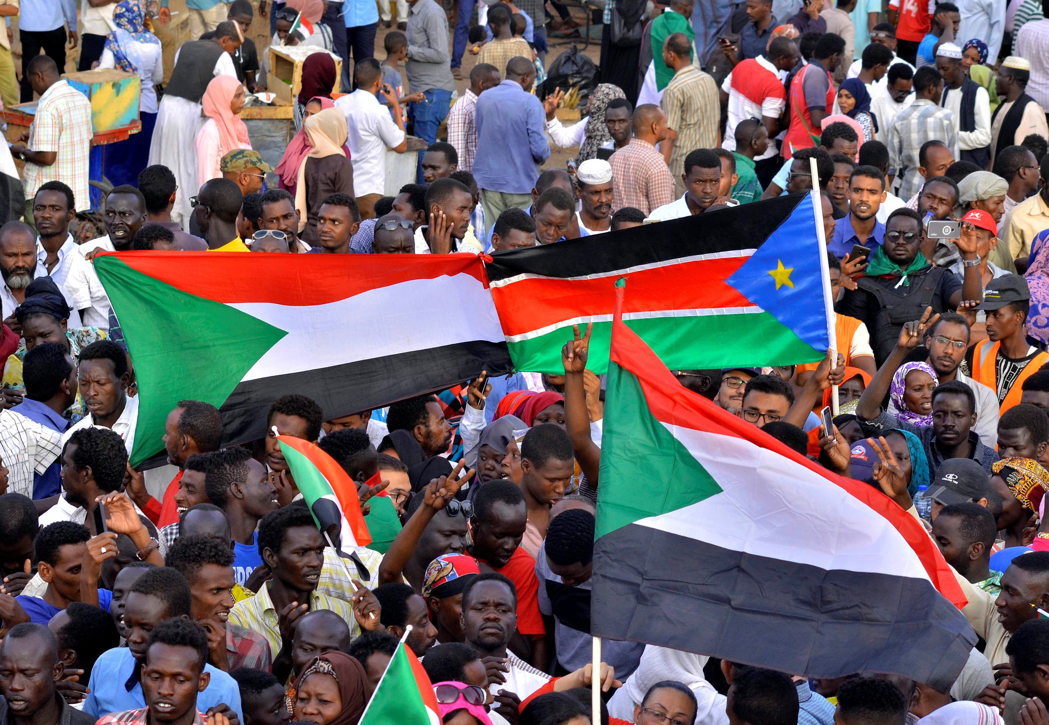   Sudanese demonstrators display their national flag and the national flag of South Sudan on 14 April (REUTERS)