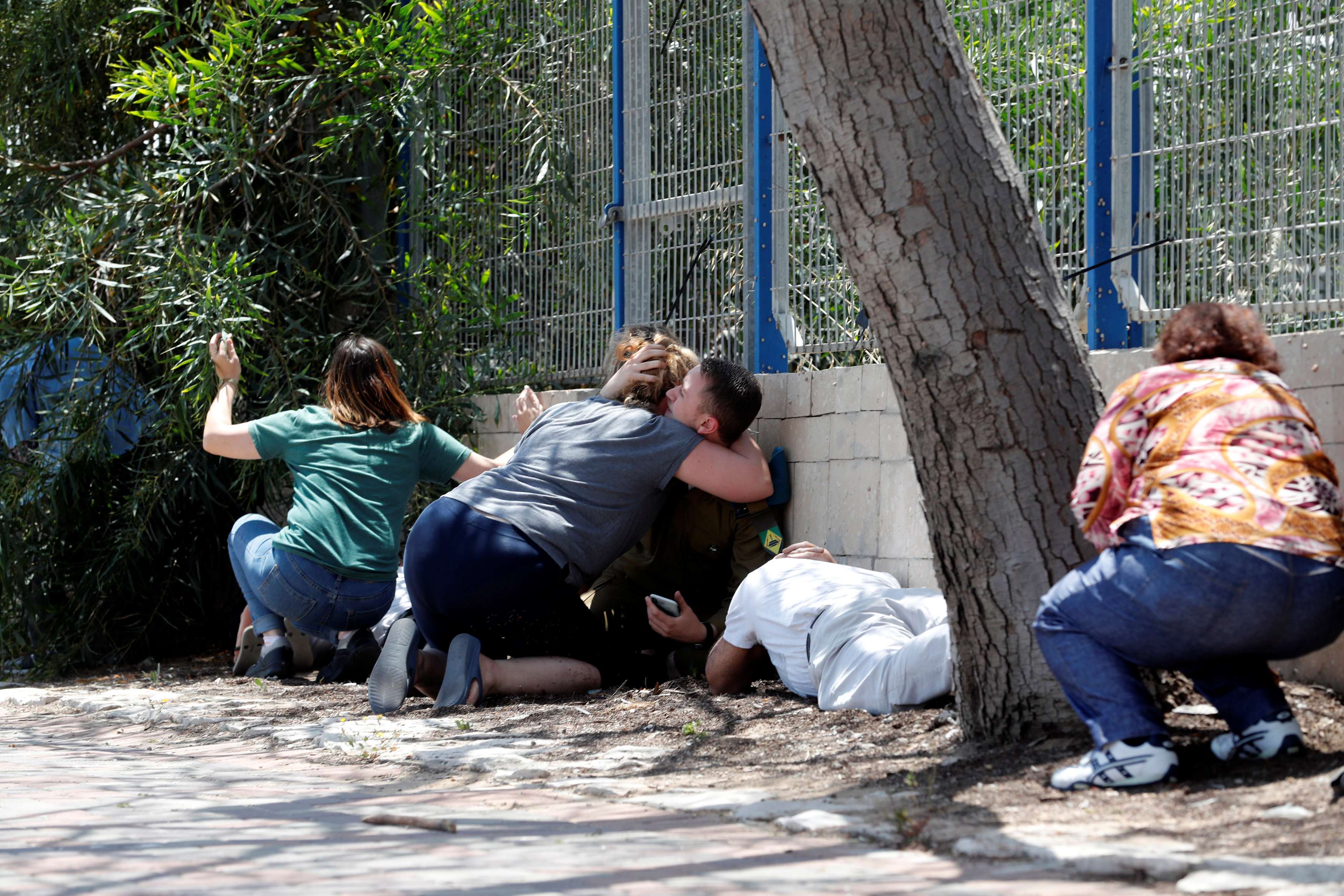 Israelis take cover as they hear sirens warning of incoming rockets from Gaza, during cross-border hostilities, in the southern Israeli city of Ashkelon (Reuters)