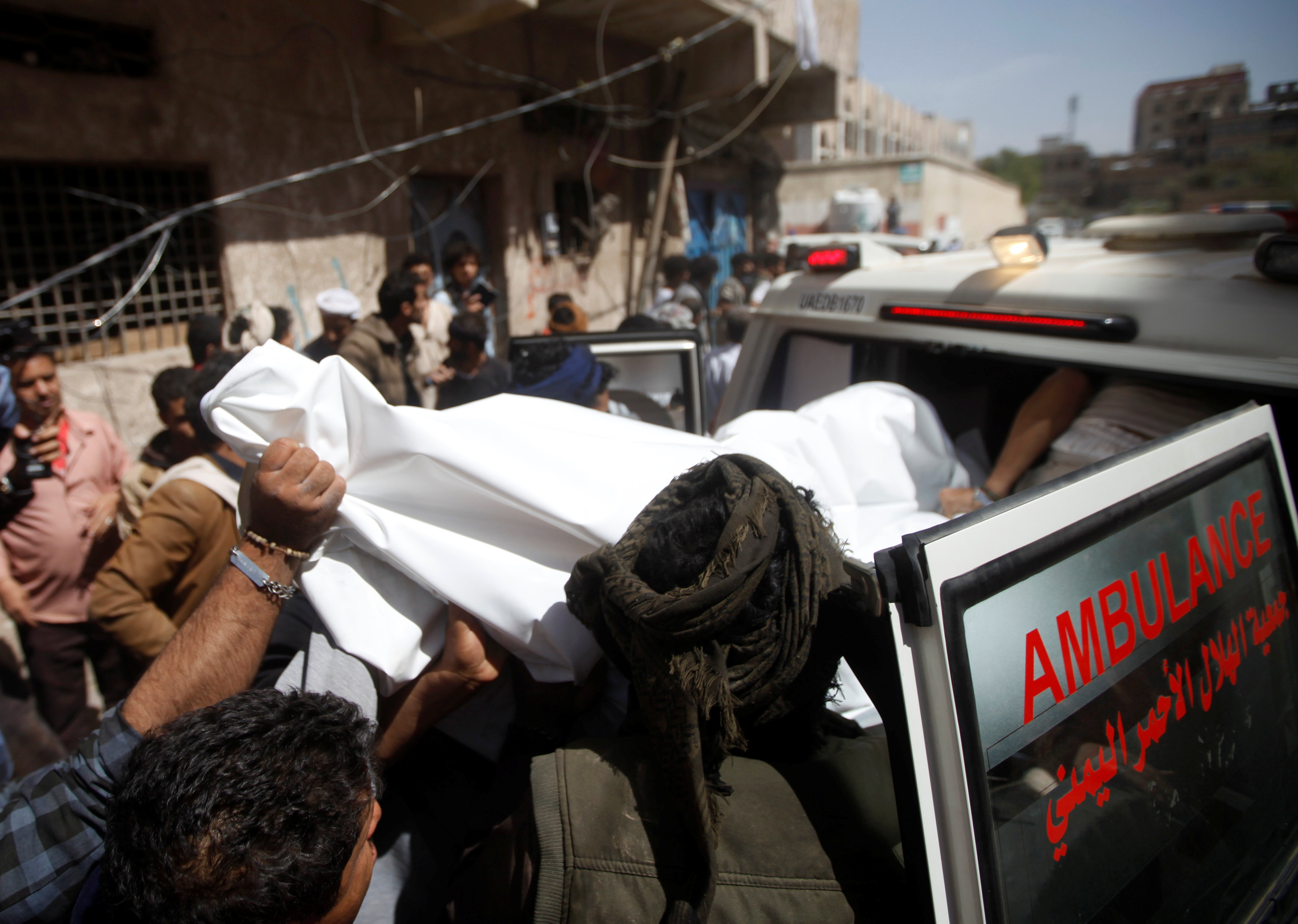 Yemeni men carry the body of a dead woman, who was killed by Saudi-led air strike in Sanaa