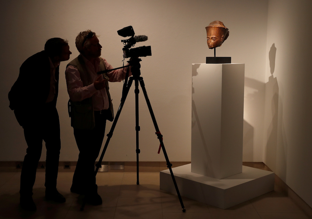 A camera crew films an Egyptian brown quartzite head of the God Amen which will be sold at auction at Christie's in London (Reuters)