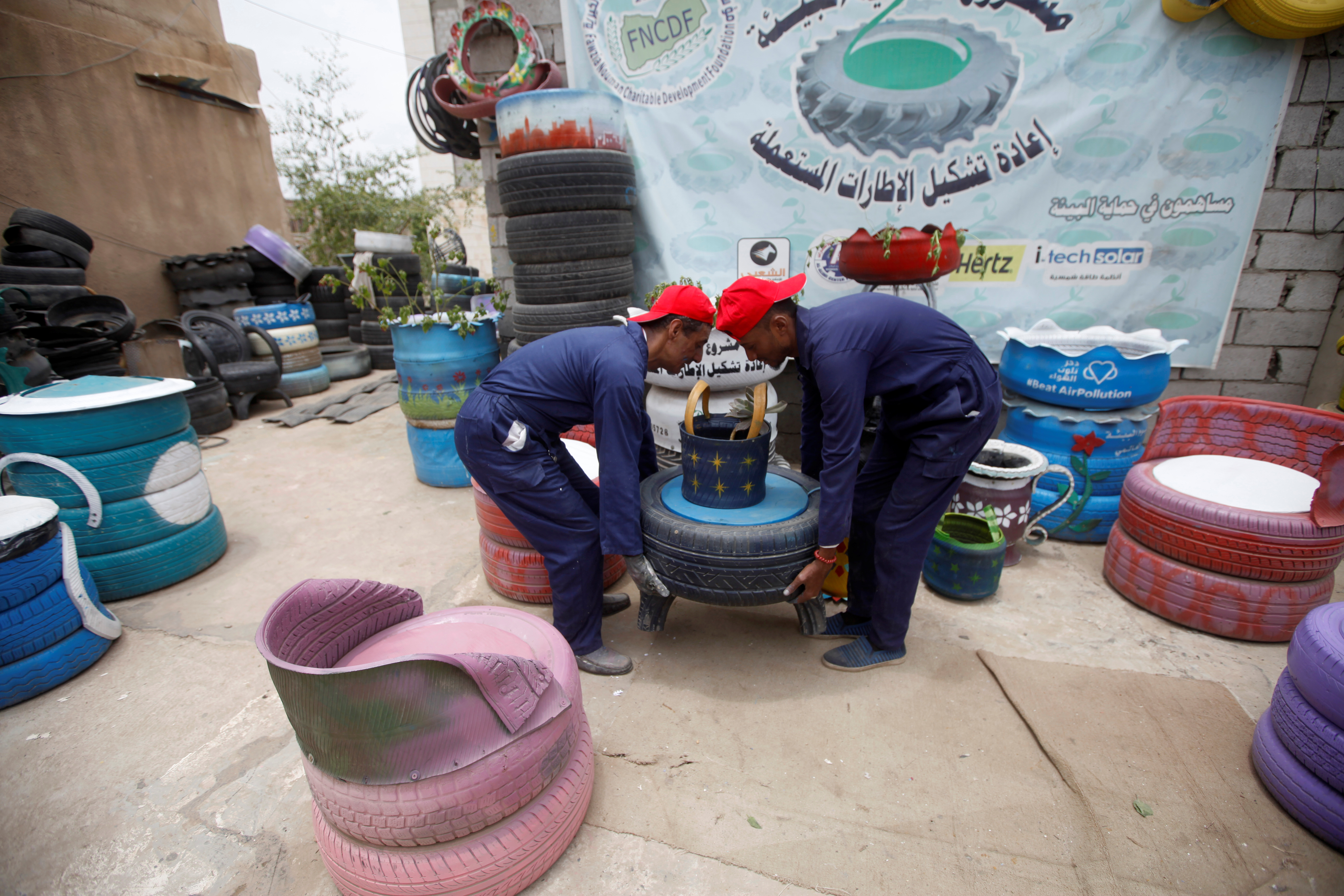 Furniture makers in Sanaa lift an item made from used tyres