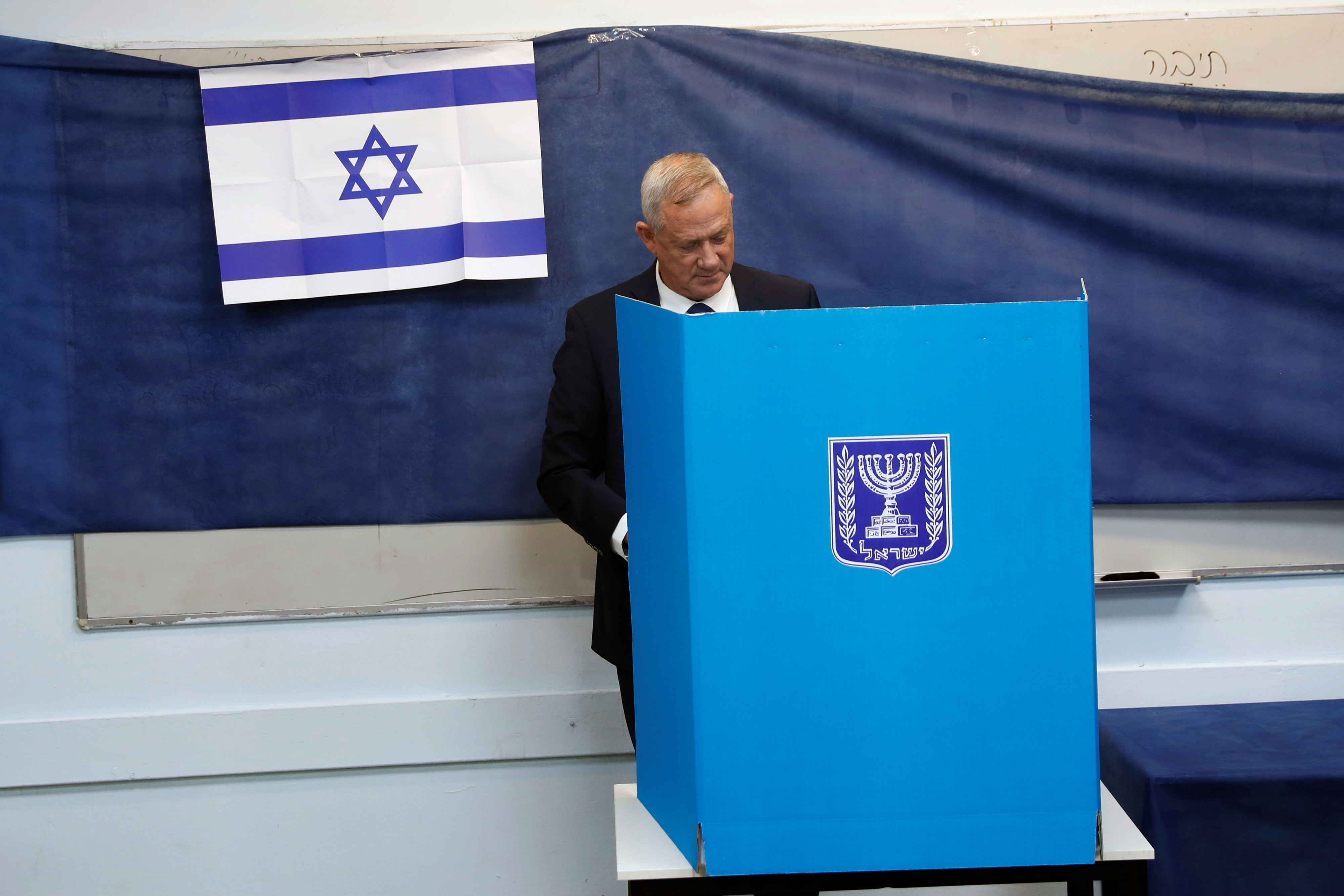 Leader of Blue and White party, Benny Gantz stands behind a voting booth as he votes in Israel's parliamentary election at a polling station in Rosh Haayin (Reuters)