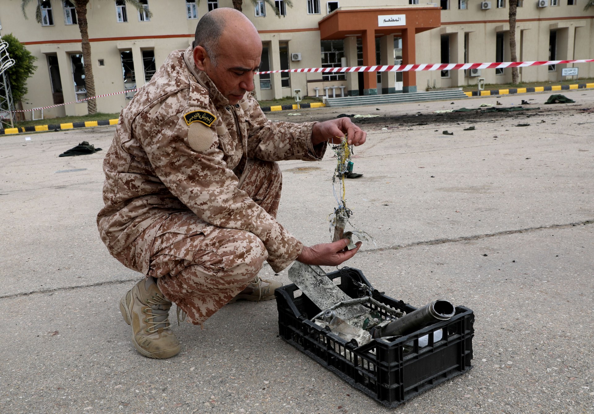 A GNA soldier on 5 January 2020 picks up shrapnel that the BBC later used to identify that a UAE-supplied drone had bombed the cadets (Reuters)