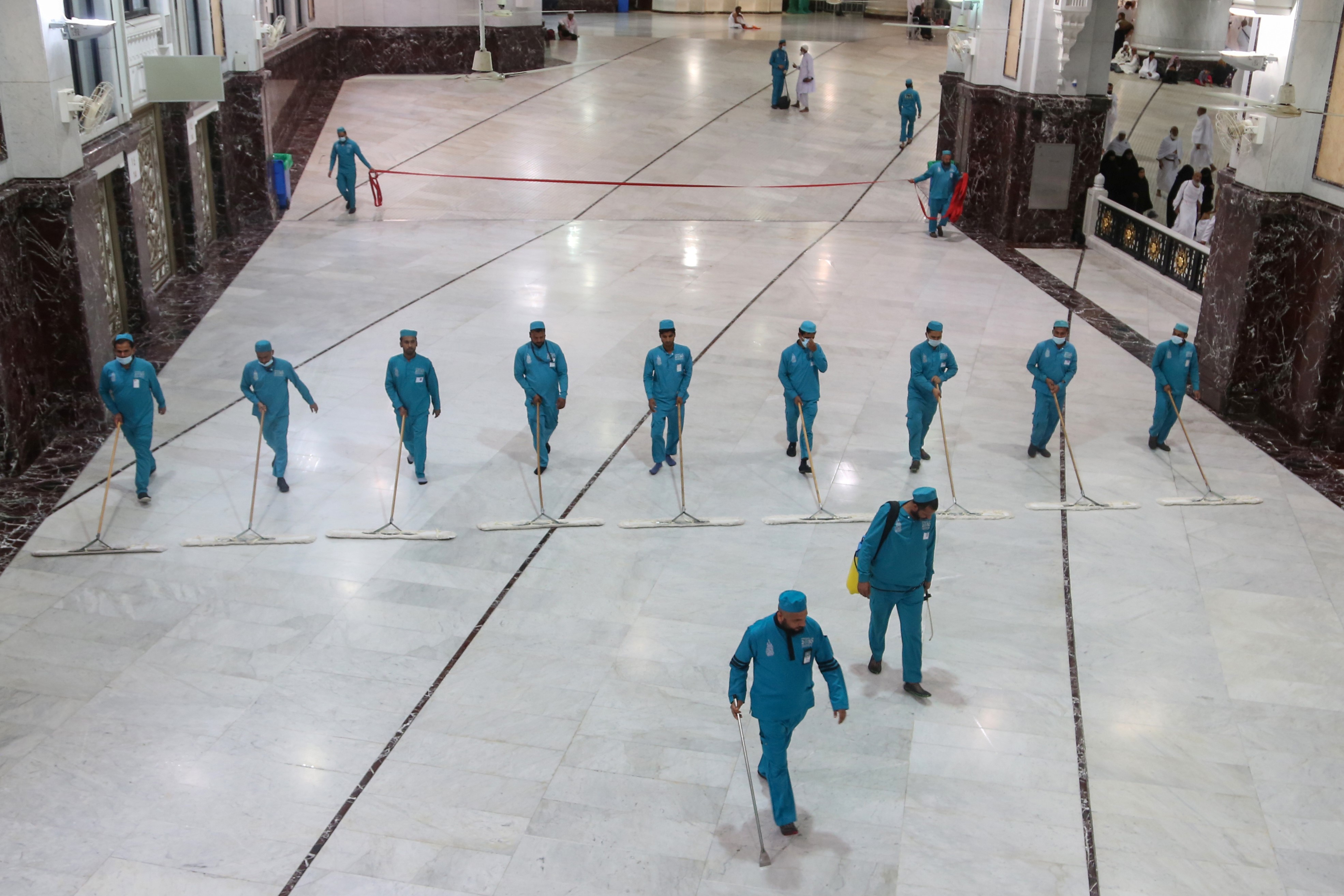 Cleaners wear protective face masks, following the outbreak of the coronavirus, as they swipe the floor at the Grand mosque in the holy city of Mecca, Saudi Arabia March 3, 2020.