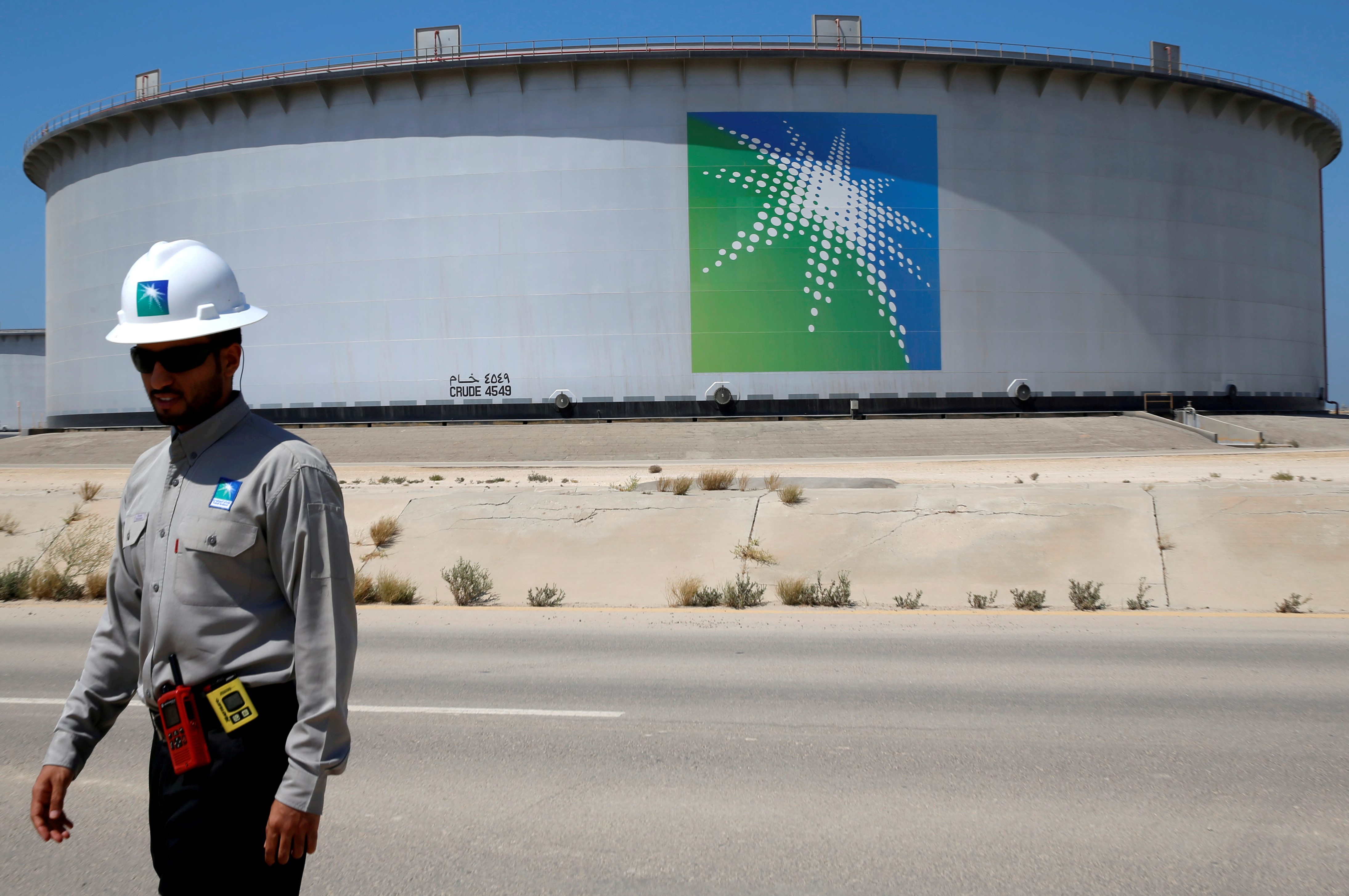 An Aramco employee walks near an oil tank at Saudi Aramco's Ras Tanura oil refinery 