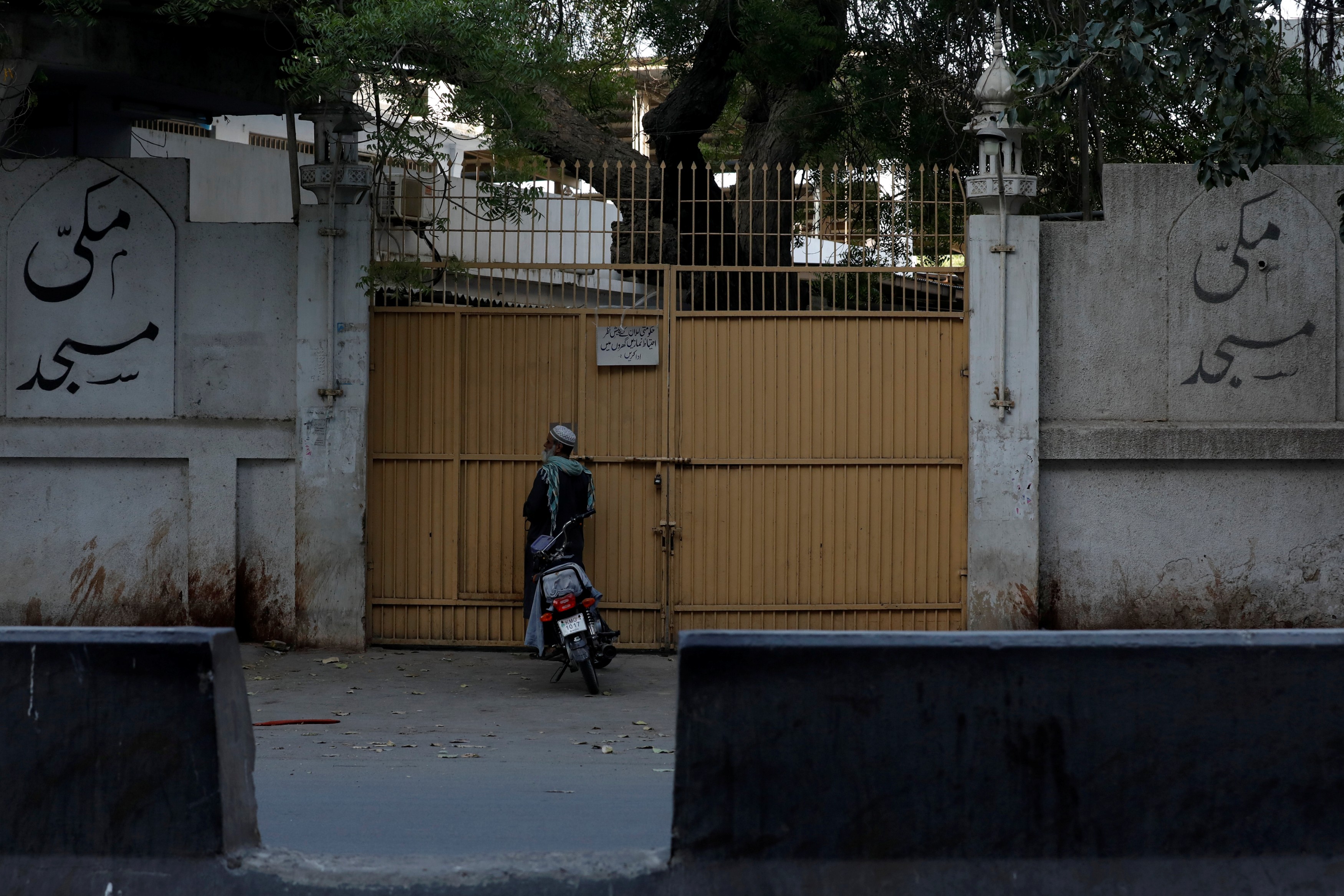 A man stands at the closed entrance of the Makki Masjid Tablighi centre in Karachi this week after the government ordered those inside to quarantine (Reuters)