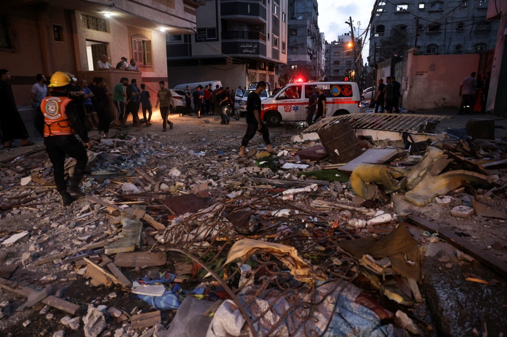 Des pompiers palestiniens de la défense civile vérifient les décombres d’un appartement détruit par les frappes aériennes israéliennes à Gaza le 11 mai 2021 (AFP)
