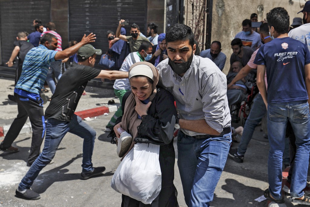 Des Palestiniens évacuent un bâtiment visé par un bombardement israélien, à Gaza, le 11 mai (AFP)