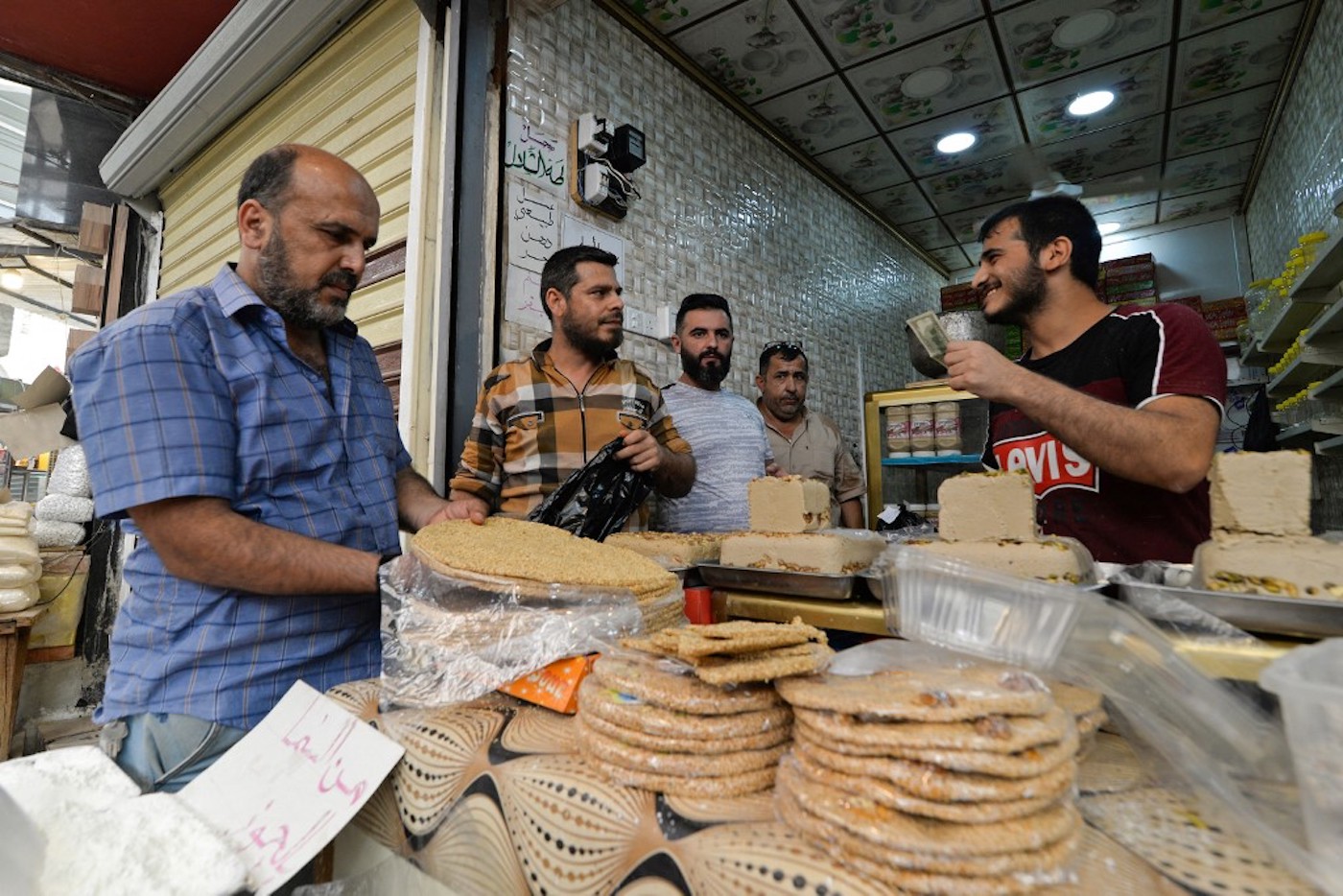 Des Irakiens achètent les douceurs traditionnelles de l’Aïd al-Adha, dans un marché au nord de Mossoul, le 17 juillet 2021 (AFP/Zaid al-Obeidi)