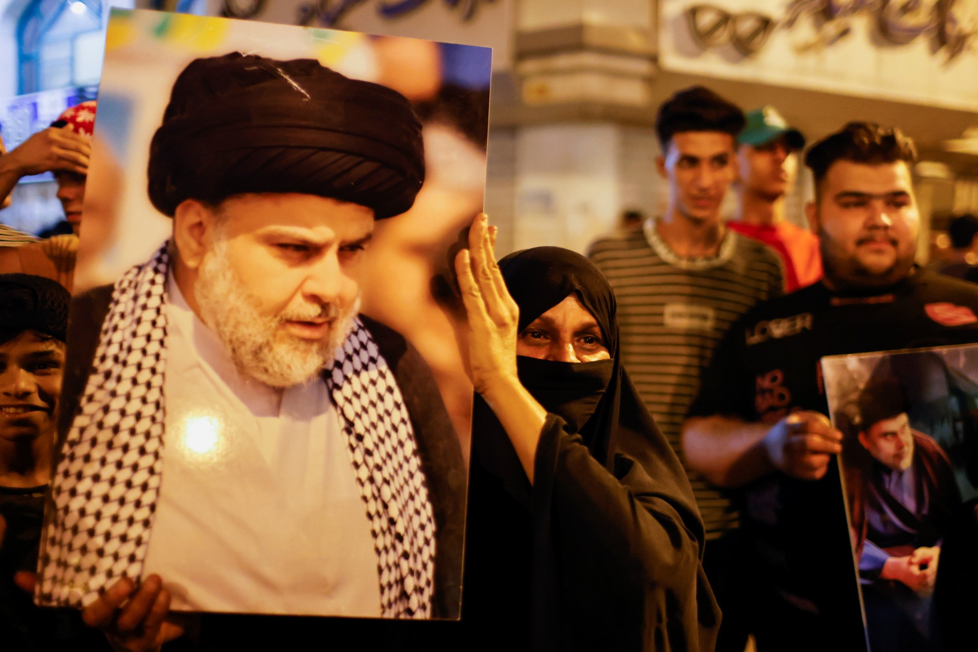 A woman holds a picture of Sadr's movement leader Moqtada al-Sadr, as his supporters celebrate after preliminary results of Iraq's parliamentary election were announced in Baghdad (Reuters)