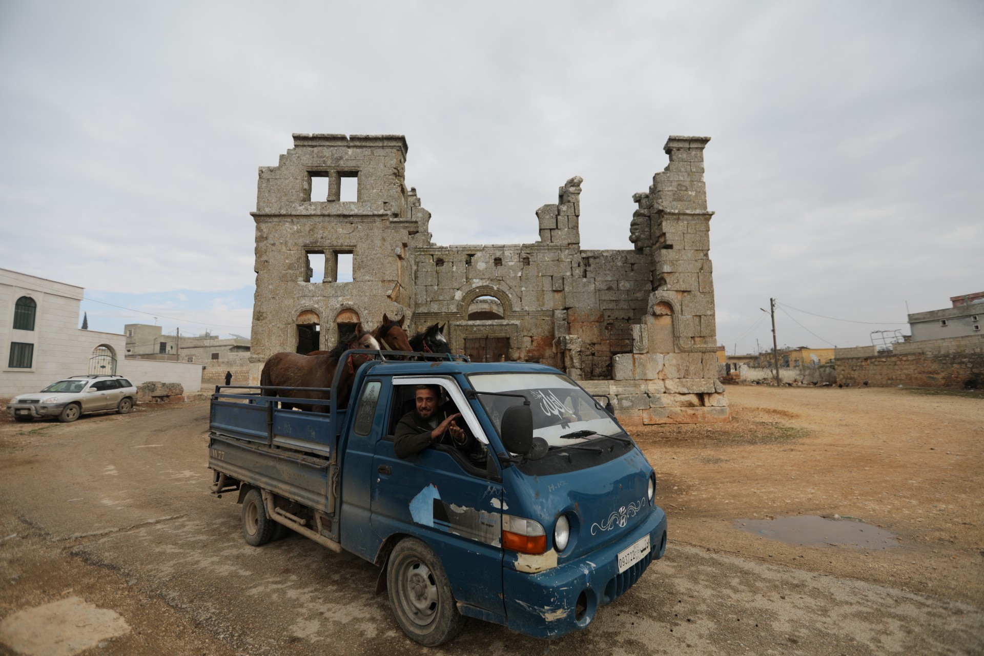 A man driving a truck carrying horses passes in front of the ancient Qalb Loze Church, Syria (Reuters)