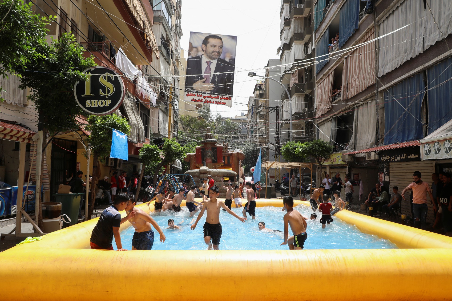 A poster depicting Lebanon's former Prime Minister Saad al-Hariri hangs as children play in an inflatable pool, in the al-Tariq al-Jadida neighbourhood of Beirut (Reuters)