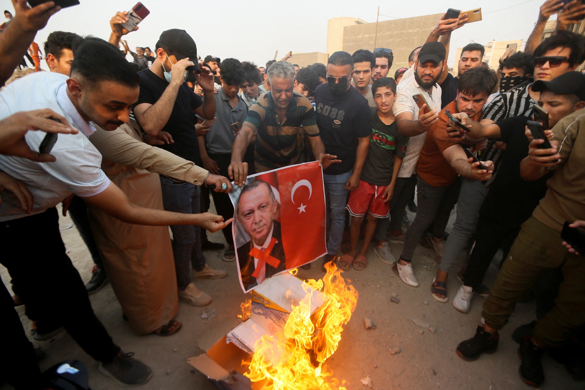 Demonstrators burn the Turkish flag in front of the Turkish consulate as they protest against the Zakho attack, in Basra on 21 July (Reuters)