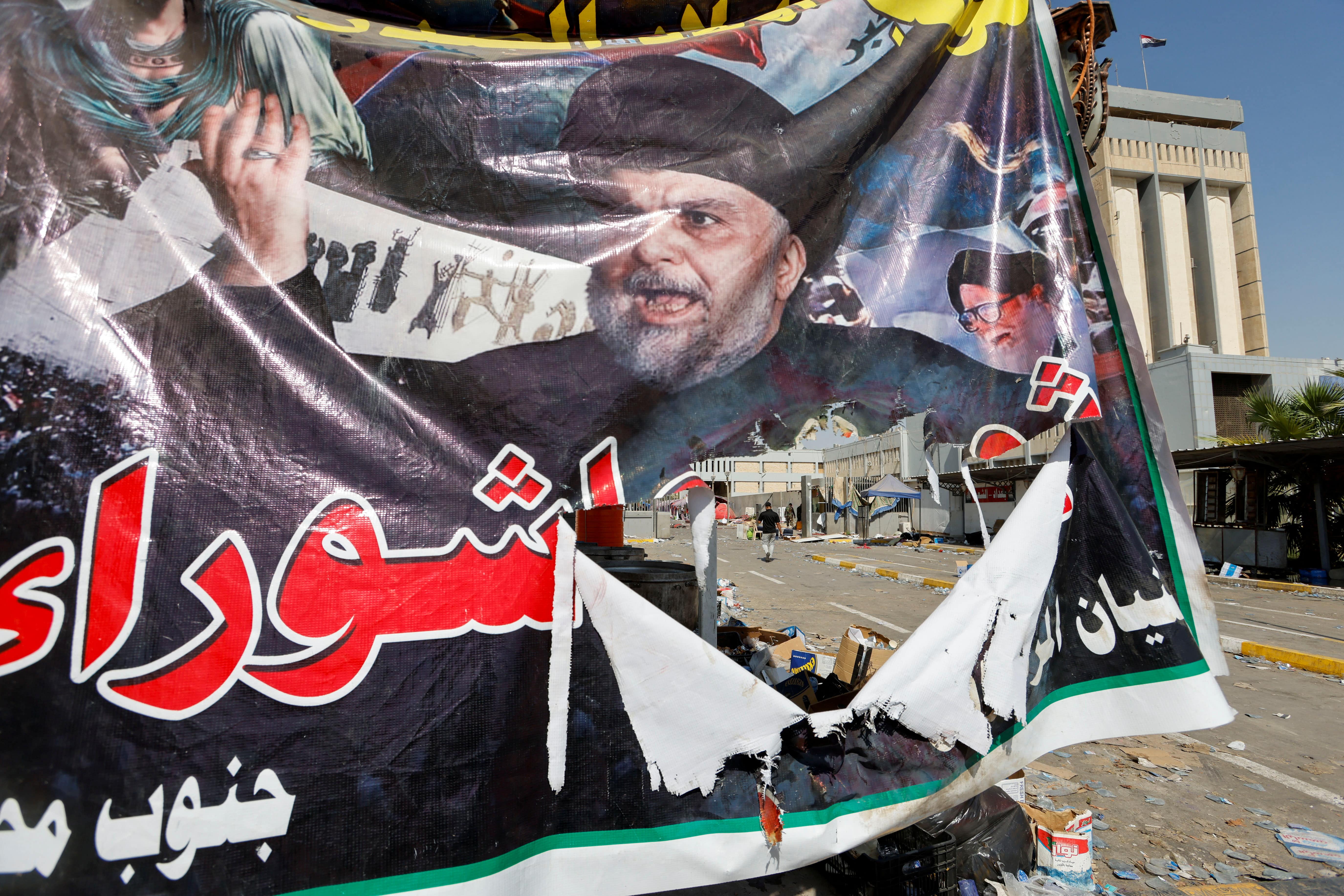 A view of a torn banner on 30 August 2022 depicting Iraqi cleric Muqtada al-Sadr in the aftermath of violent clashes between rival Shia groups at the Green Zone in Baghdad (Reuters)
