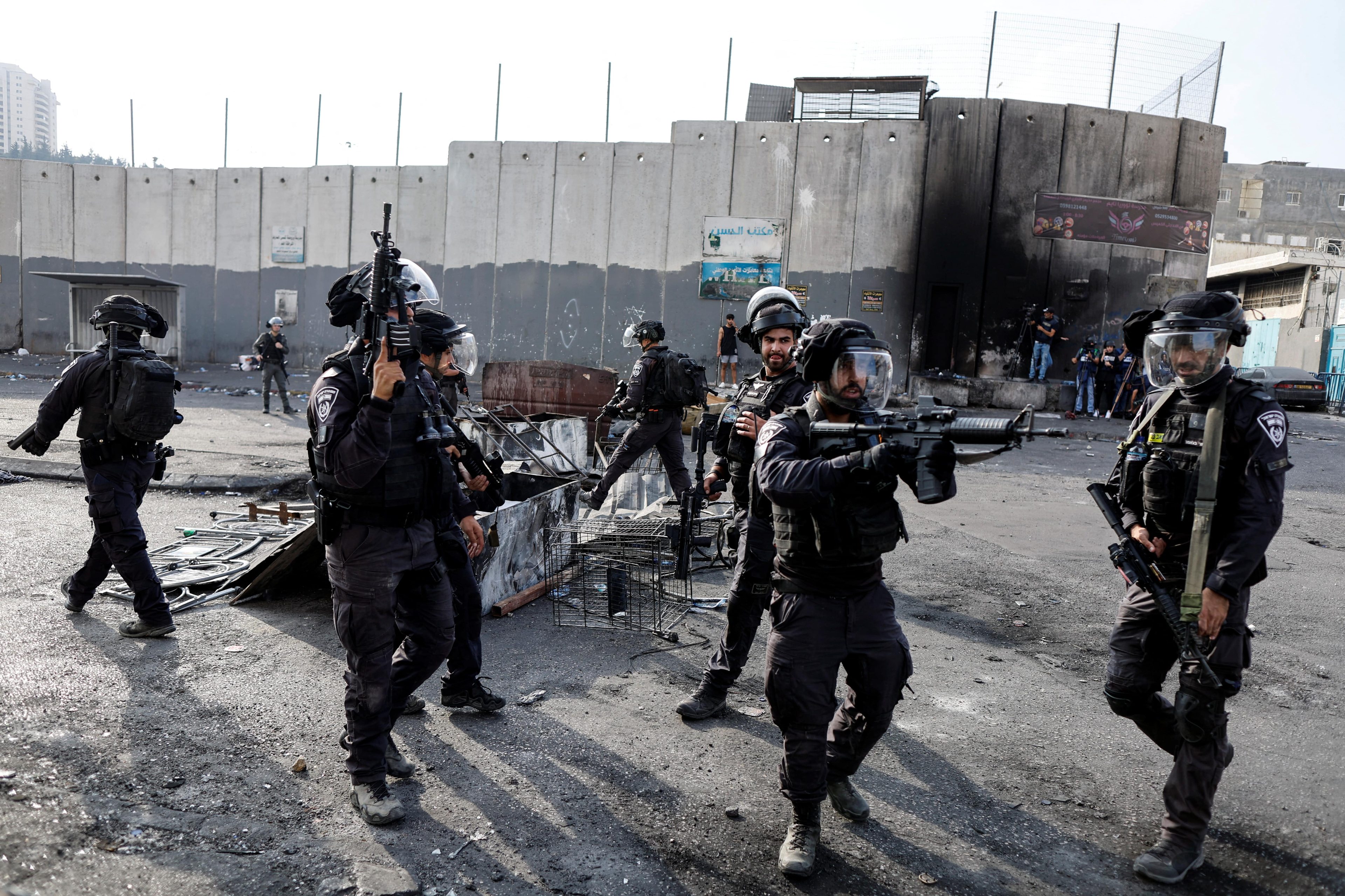 Israeli officers wield their weapons at Palestinians in the Shuafat refugee camp in East Jerusalem 12 October 2022 (Reuters)